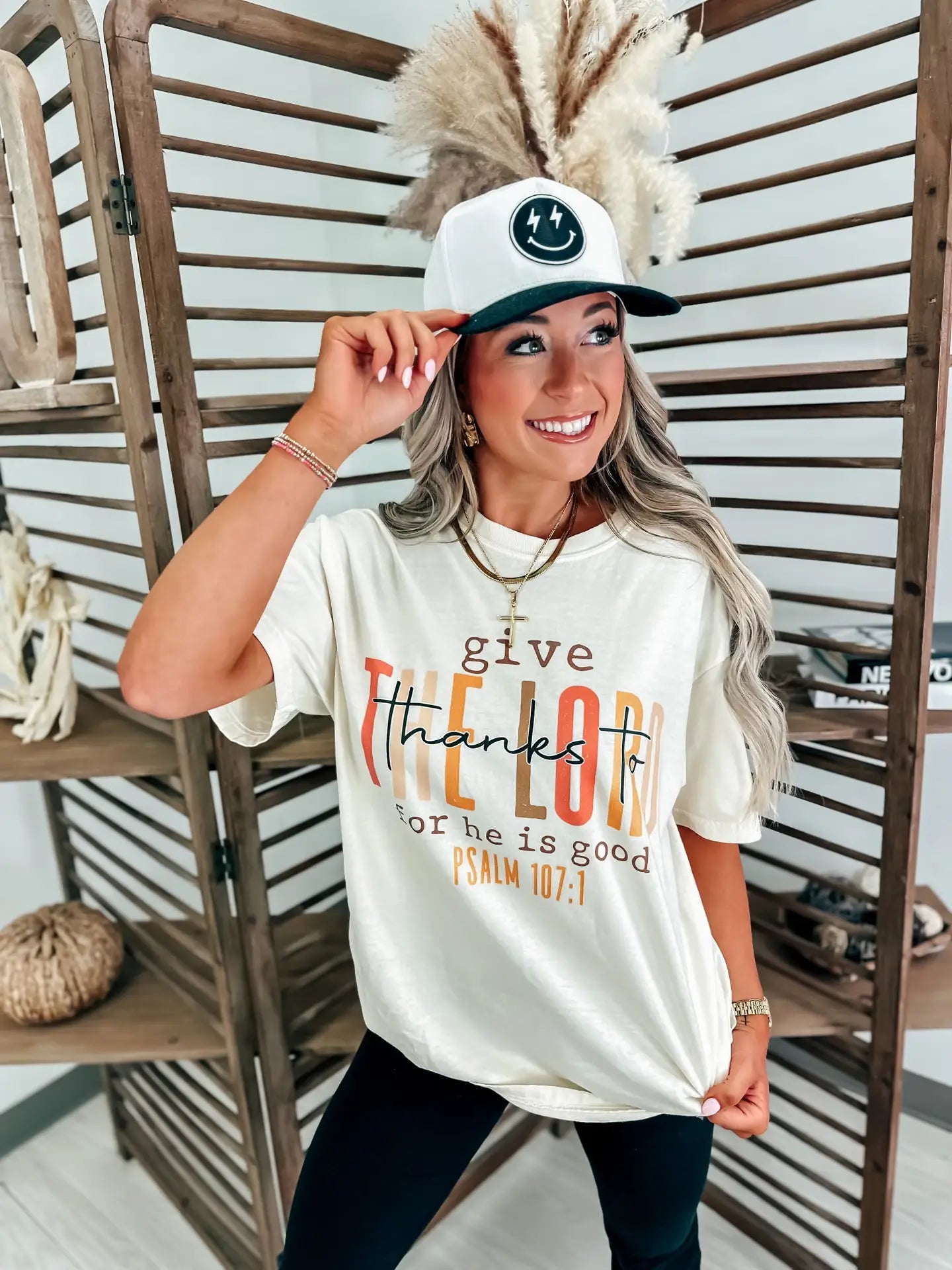 Woman wearing a cream t-shirt that reads 'give thanks to the Lord for he is good. Psalm 107:1'