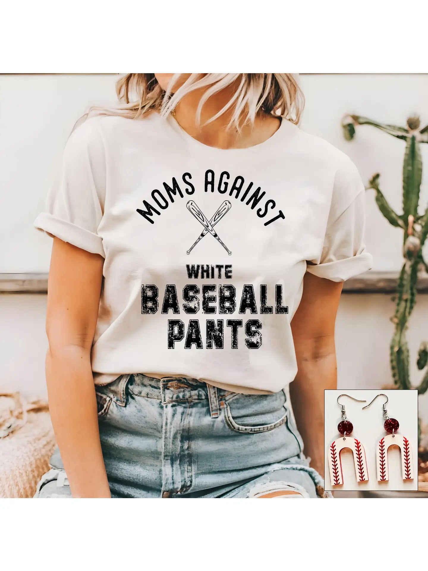 A person wearing a white graphic tee with the text 'MOMS AGAINST WHITE BASEBALL PANTS' .