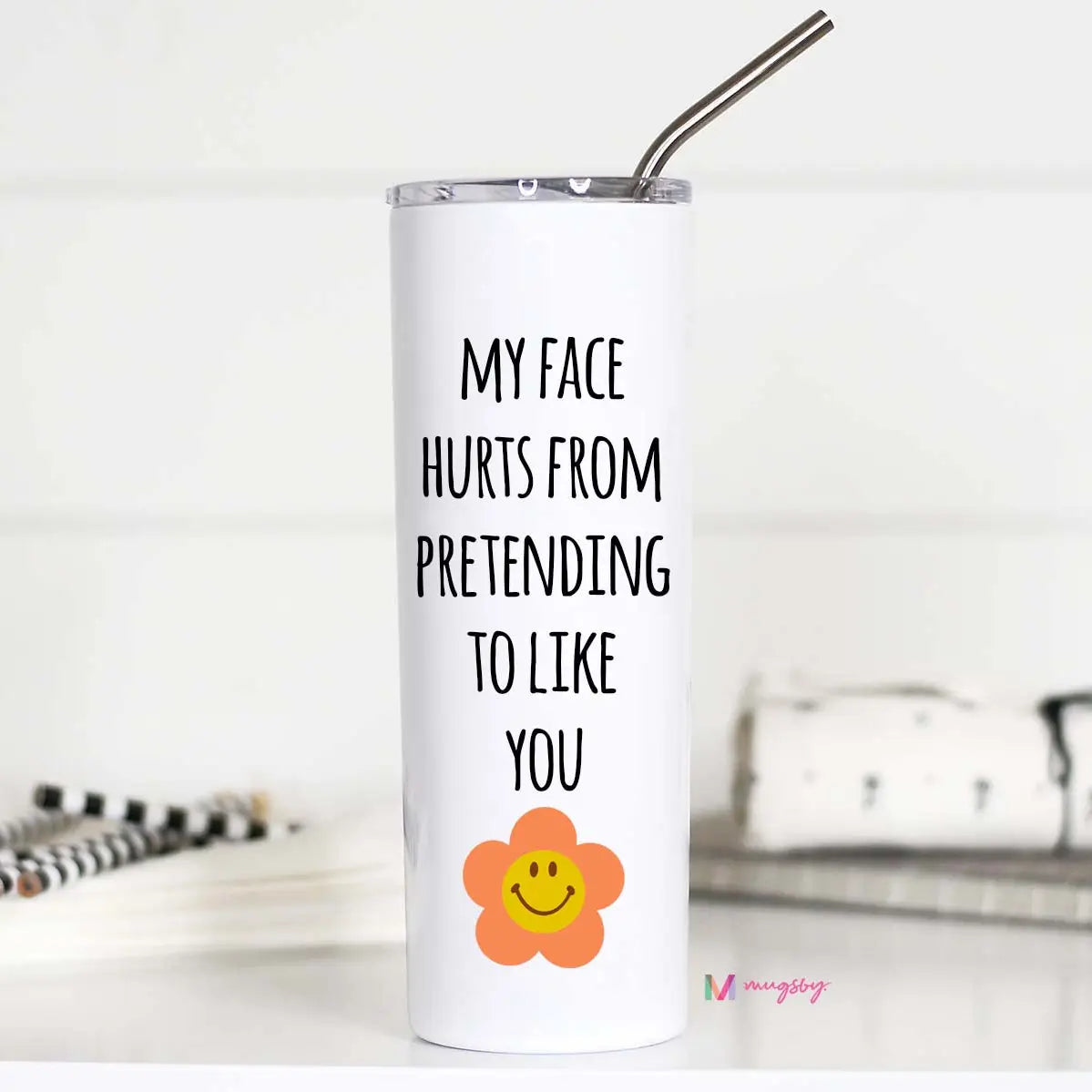 Tall stainless steel travel mug that reads 'My face hurts from pretending to like you' along with a lid and metal straw.