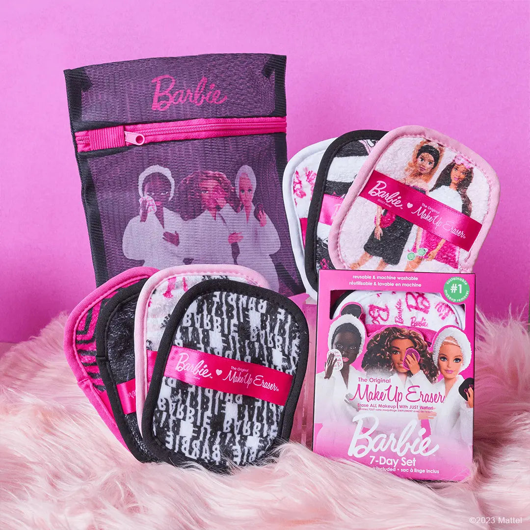 Set of seven MakeUp Eraser cloths with Barbie print, alongside a packaging box and a laundry bag, displayed on a pink surface.