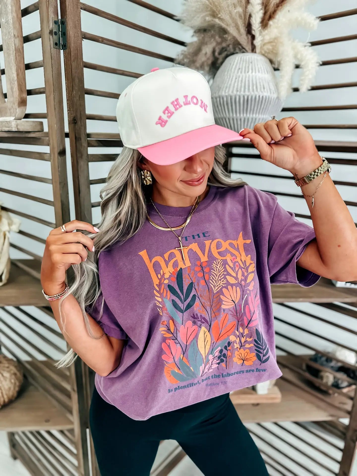 Woman wearing a purple t-shirt with floral designs that reads 'The Harvest is Plentiful, but the Laborers are Few, Matthew 9:37'