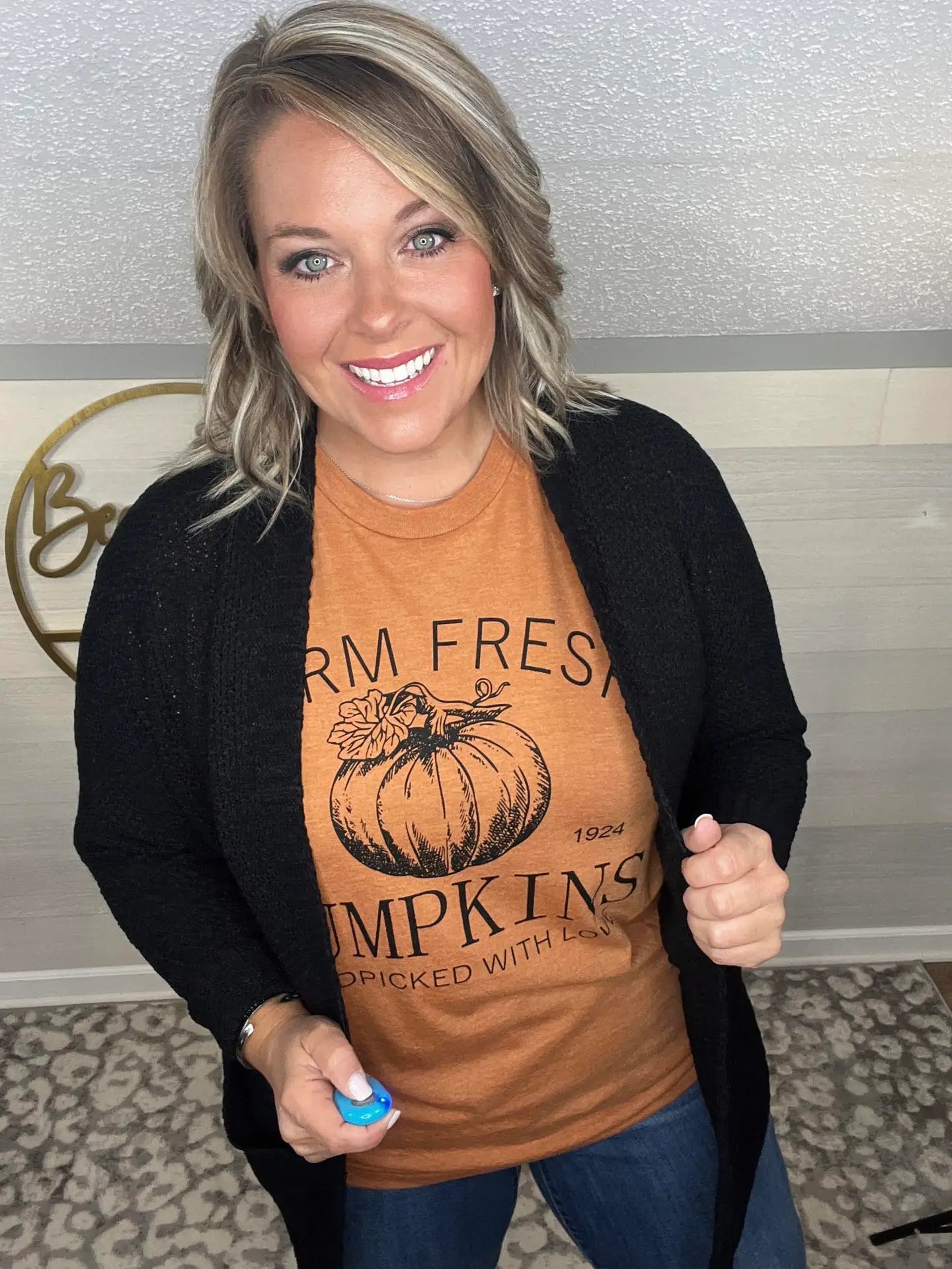 Woman wearing an orange t-shirt that says 'Farm Fresh Pumpkins, Handpicked with Love, Est. 1924' with a pumpkin graphic.