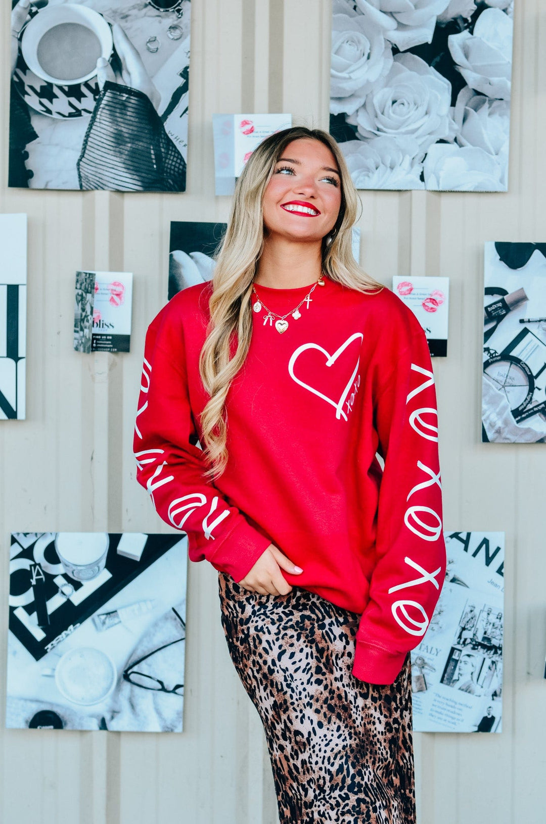 A person wearing a red sweatshirt with white text 'XOXO' on the front and down the sleeves.