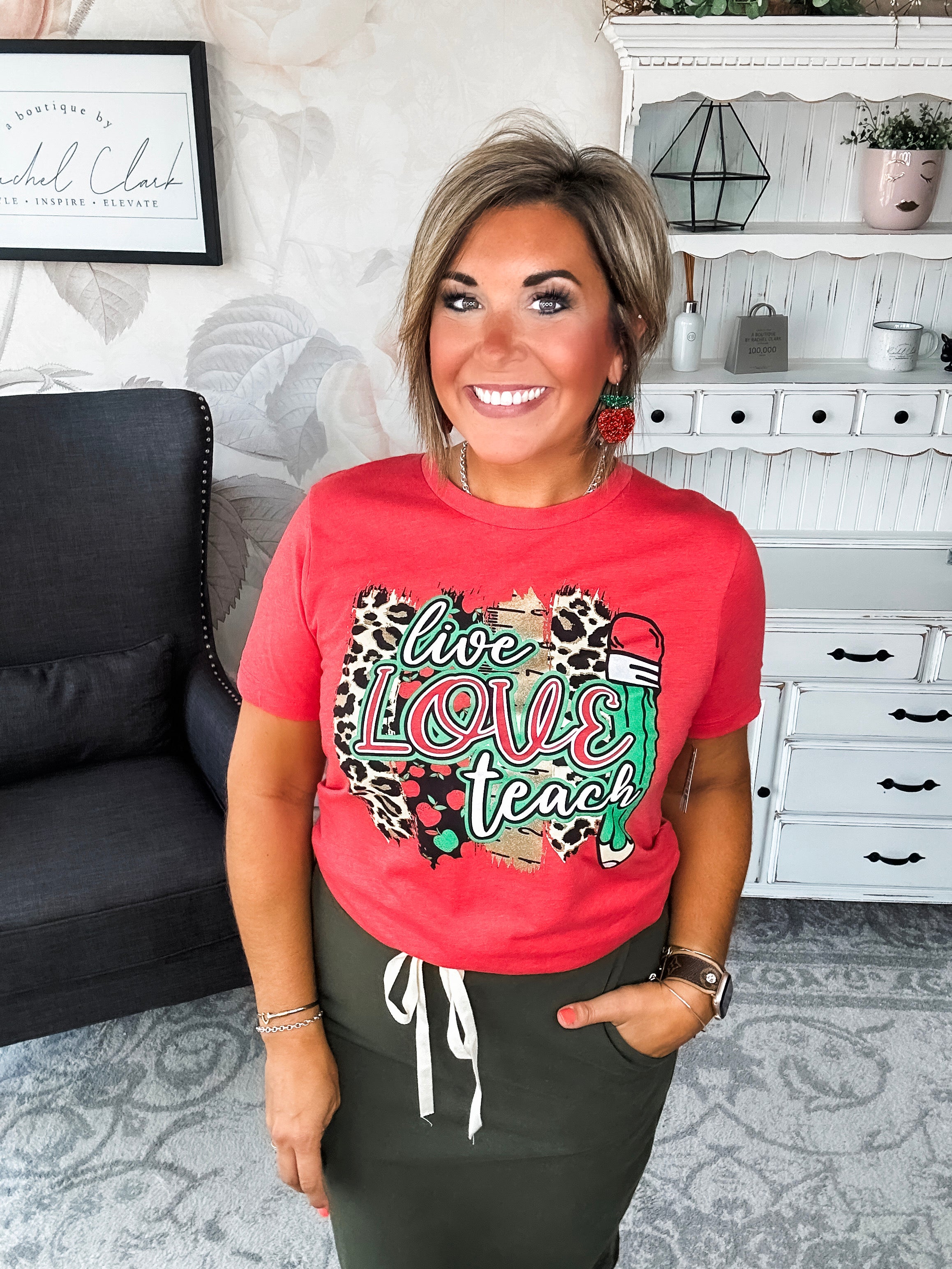 Woman wearing a red t-shirt with 'live love teach' design.