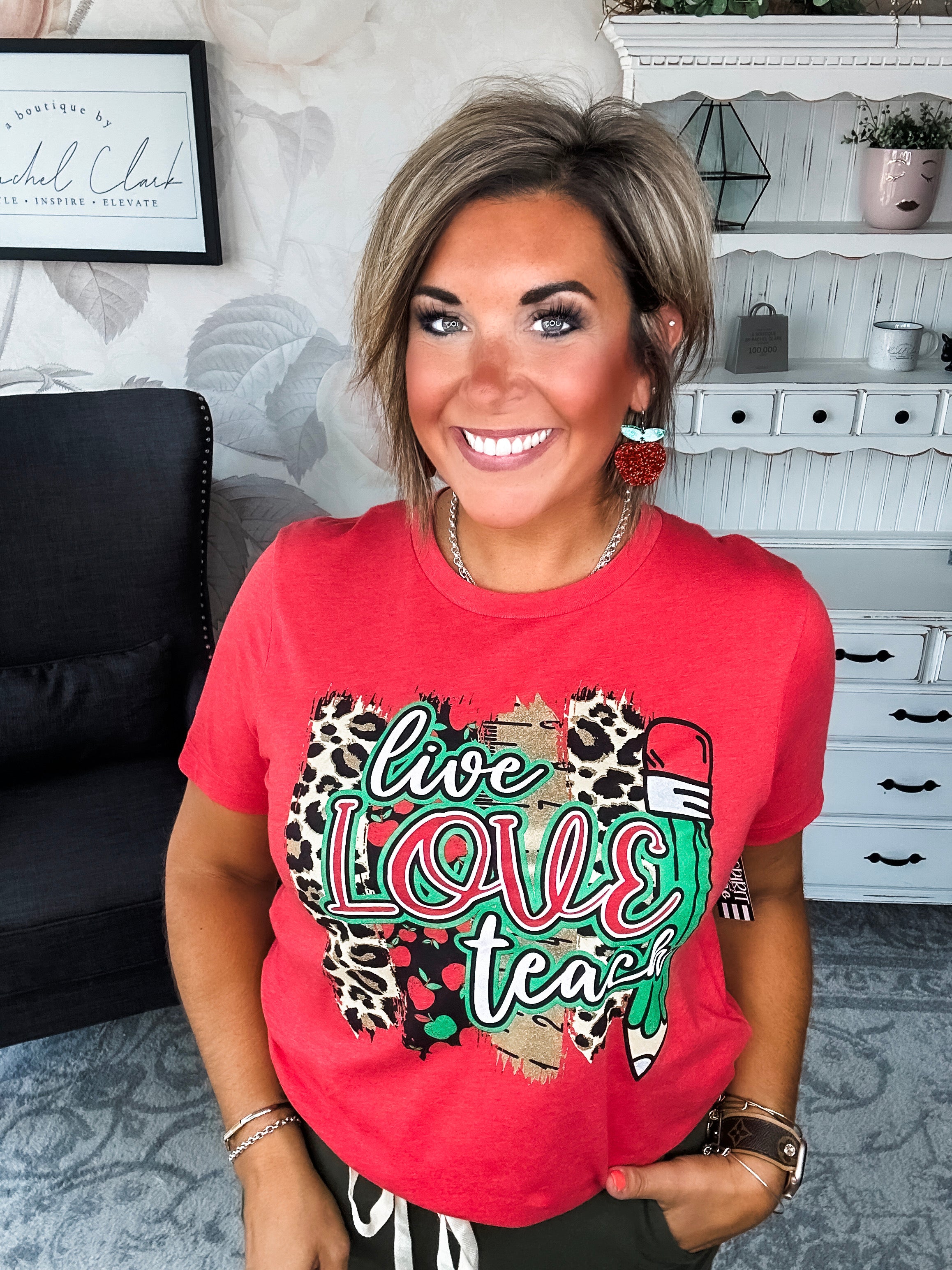 Woman wearing a red t-shirt with 'live love teach' design.