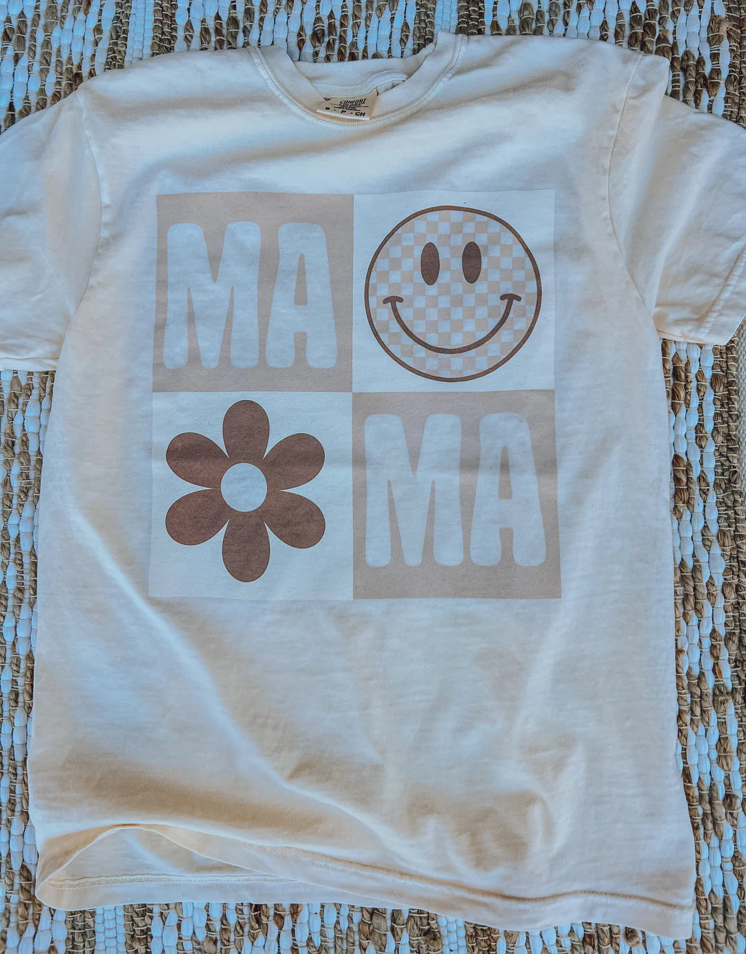A cream crew-neck t-shirt with a smiley face graphic and text that reads 'MAMA'.