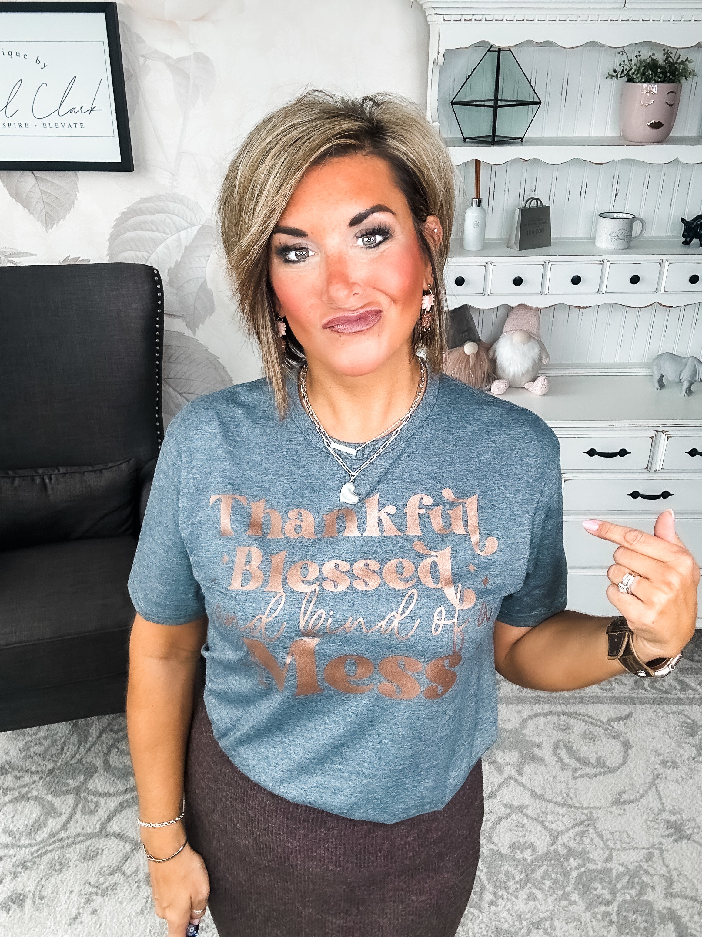 A woman wearing a grey t-shirt with the text 'Thankful Blessed and kind of a Mess' written in rose gold foil print.