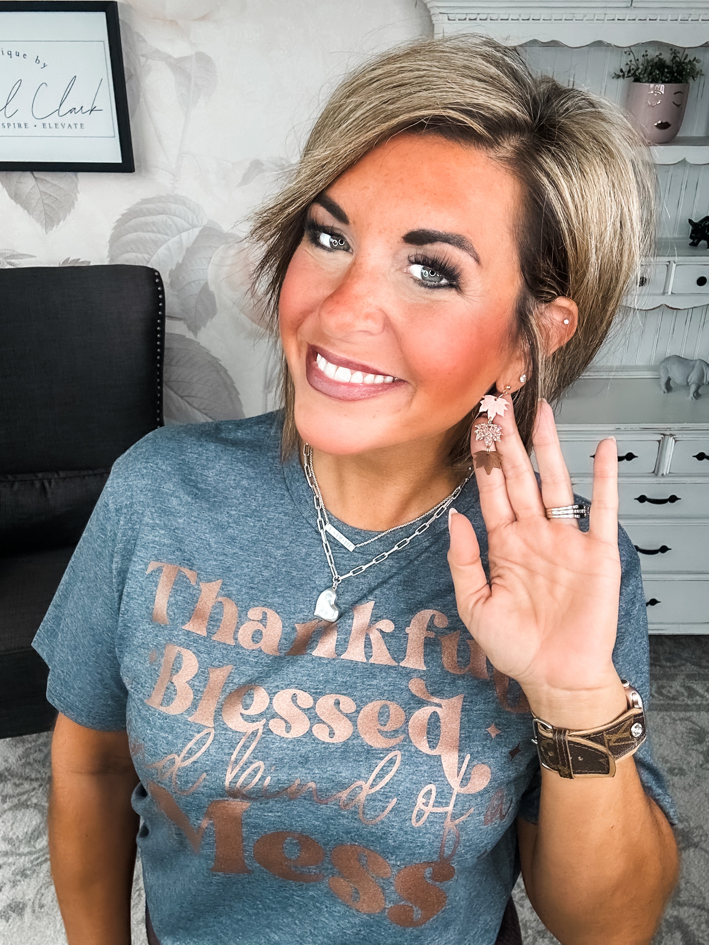 A woman wearing a grey t-shirt with the text 'Thankful Blessed and kind of a Mess' written in rose gold foil print.