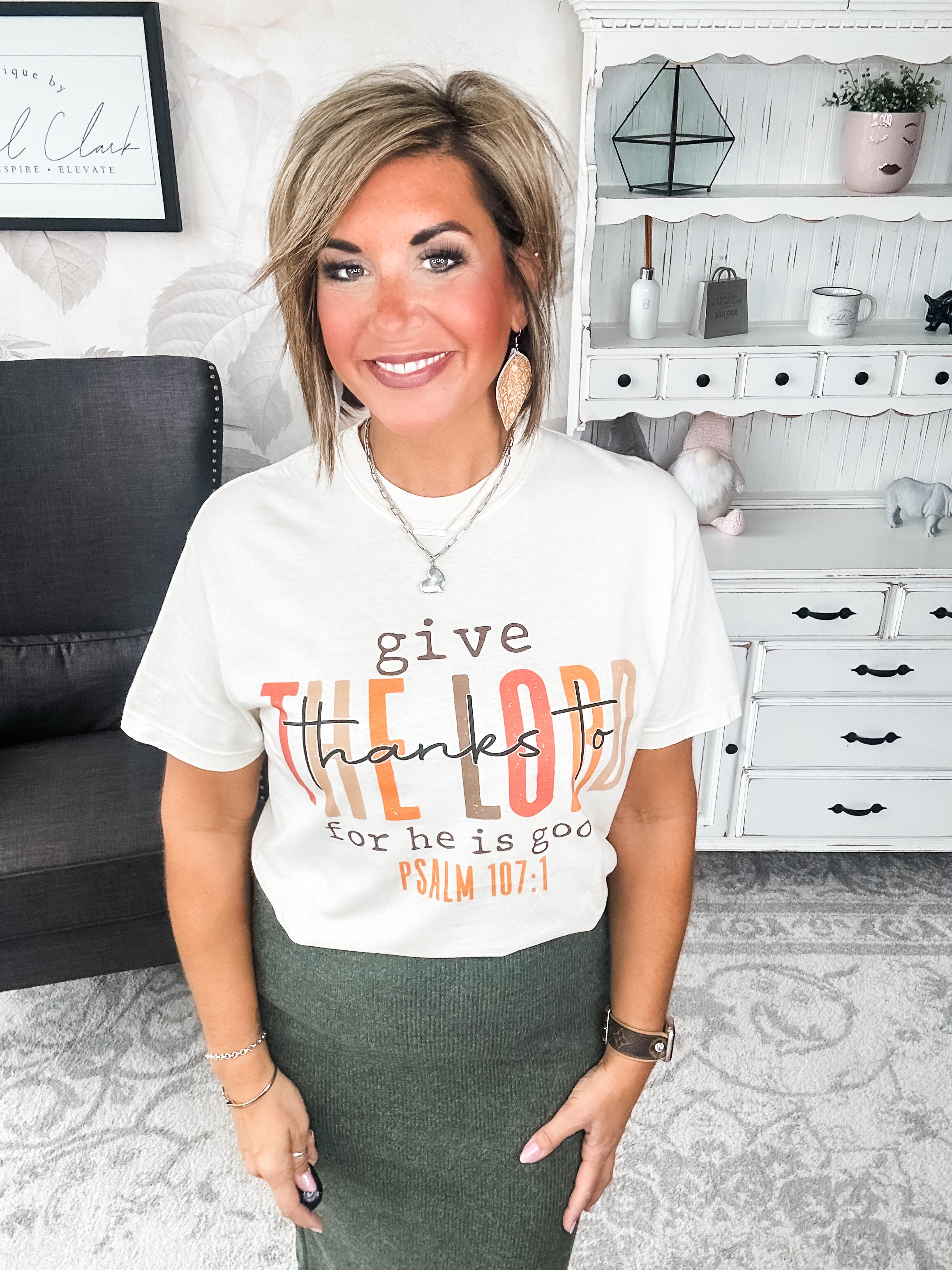 Woman wearing a cream t-shirt that reads 'give thanks to the Lord for he is good. Psalm 107:1'