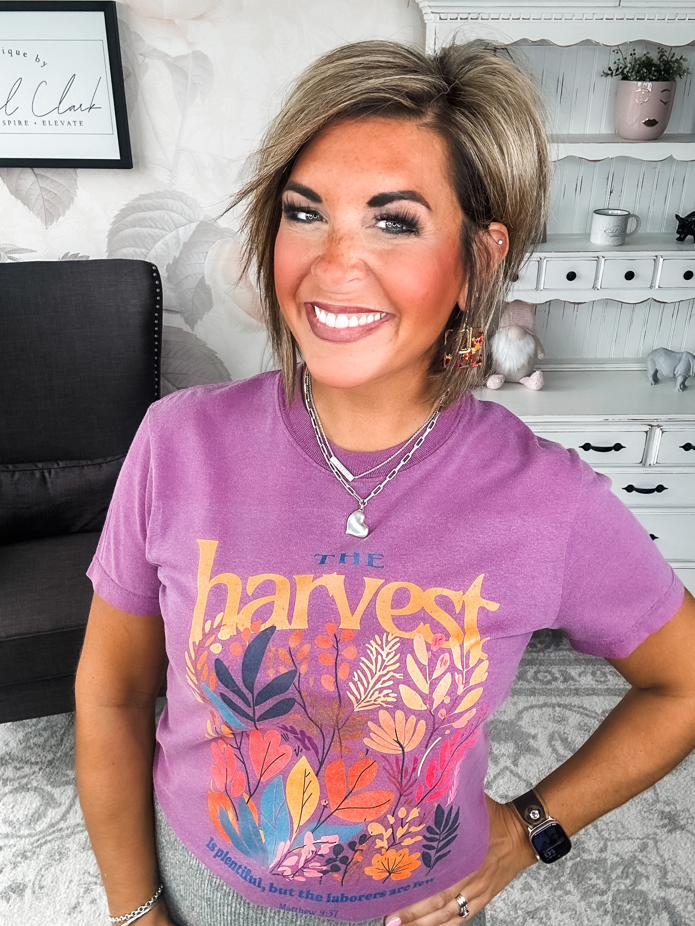 Woman wearing a purple t-shirt with floral designs that reads 'The Harvest is Plentiful, but the Laborers are Few, Matthew 9:37'