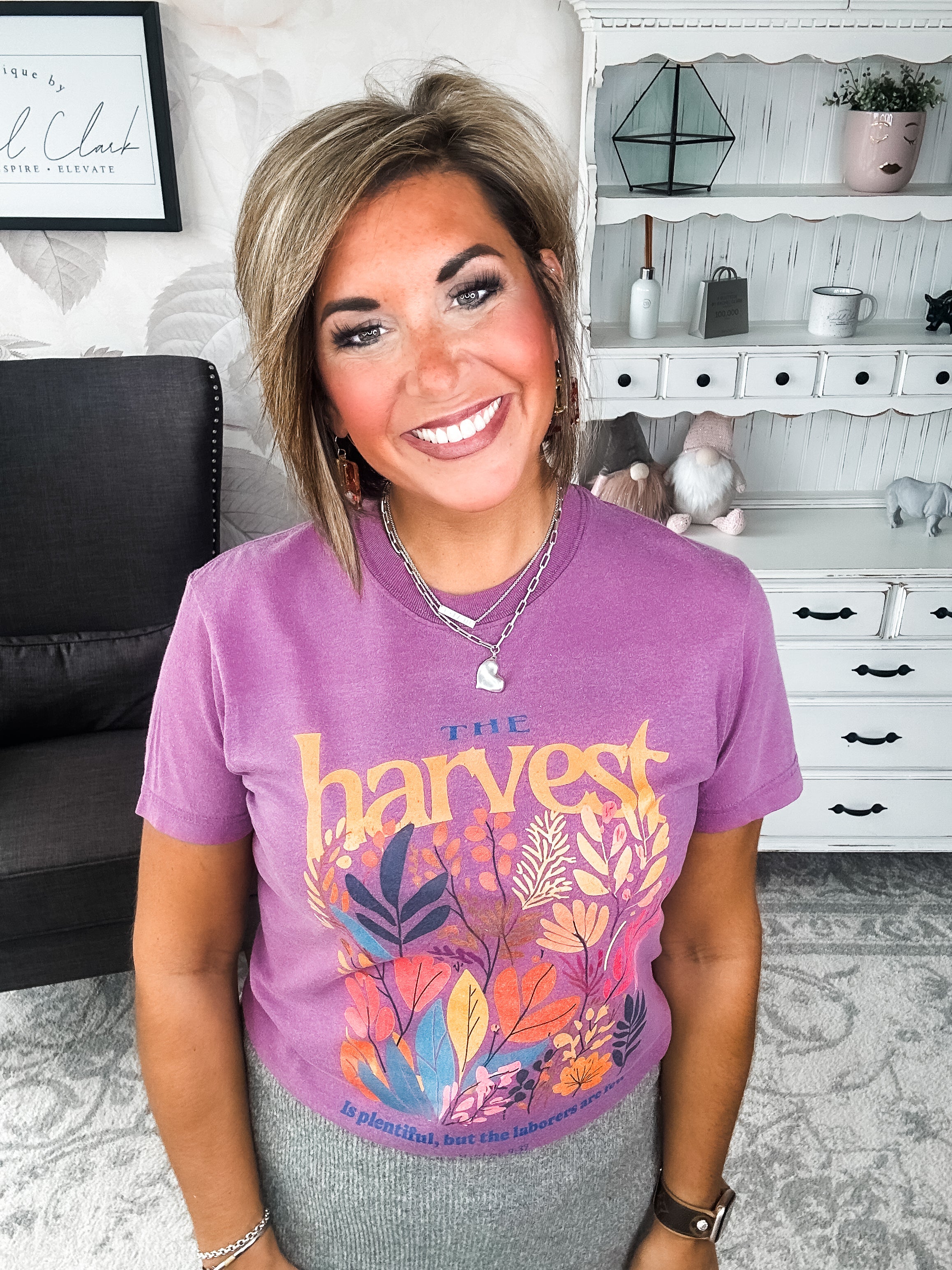 Woman wearing a purple t-shirt with floral designs that reads 'The Harvest is Plentiful, but the Laborers are Few, Matthew 9:37'