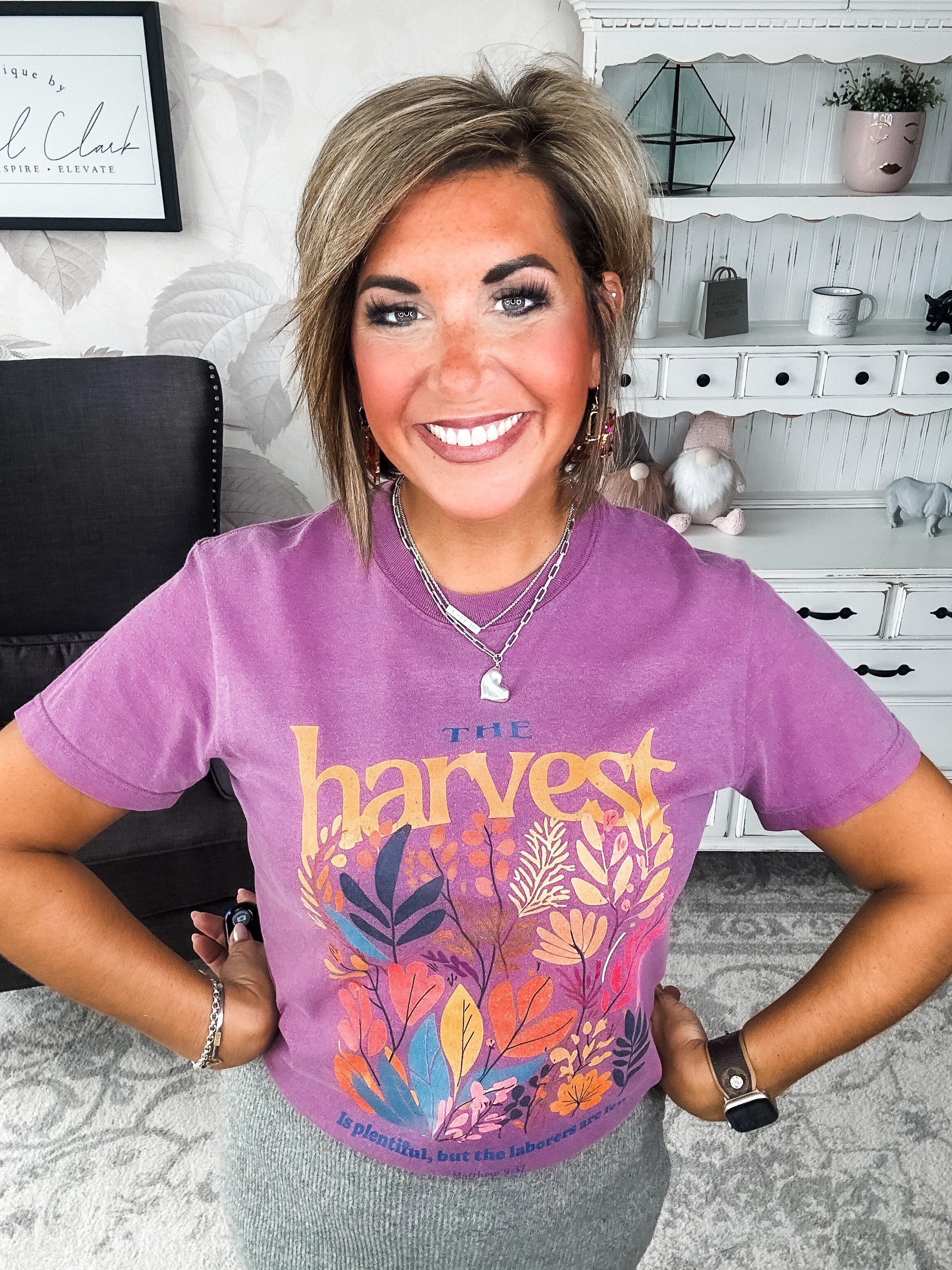 Woman wearing a purple t-shirt with floral designs that reads 'The Harvest is Plentiful, but the Laborers are Few, Matthew 9:37'