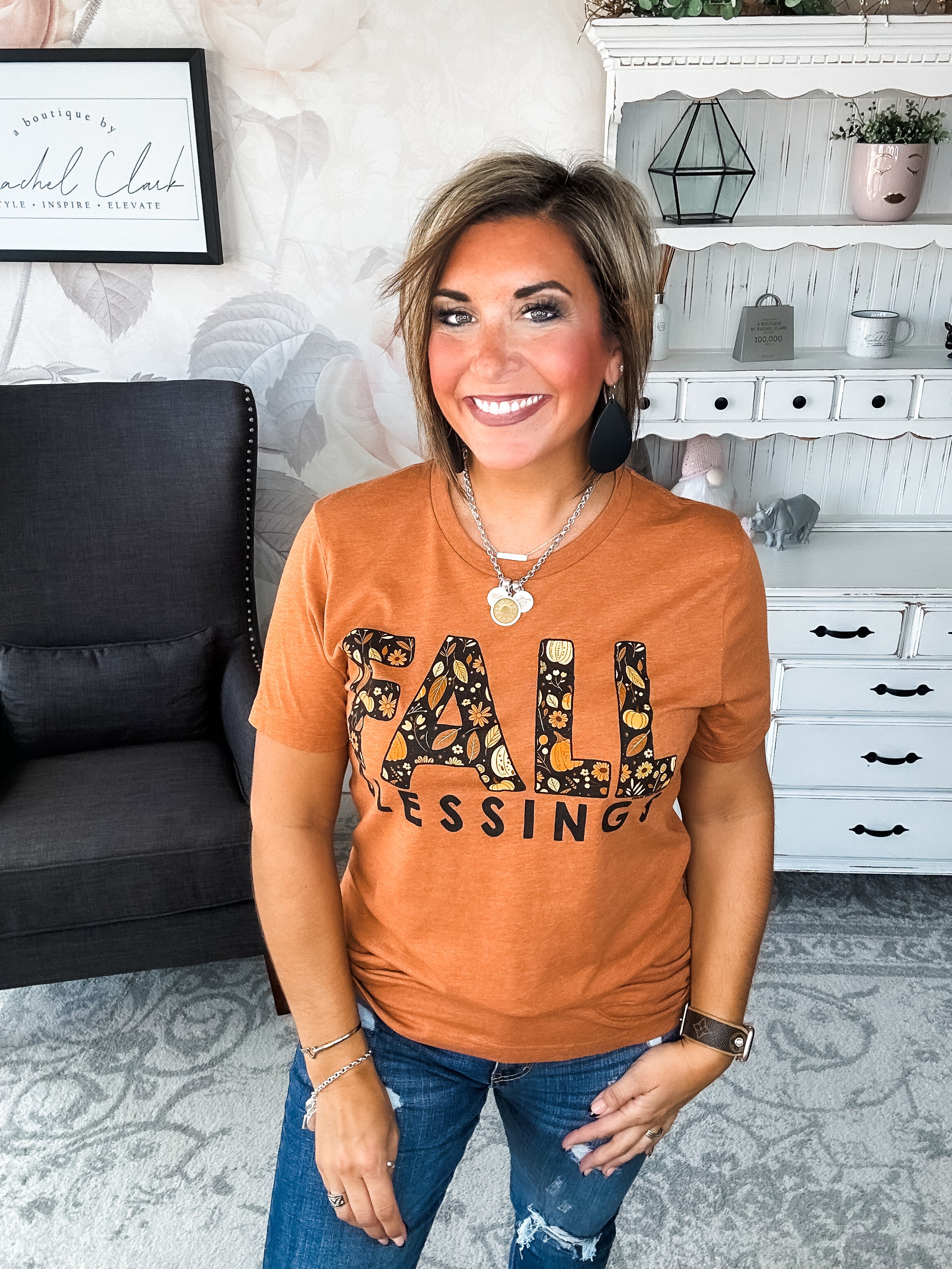 Woman wearing an orange t-shirt with 'Fall Blessings' with a leaf design.