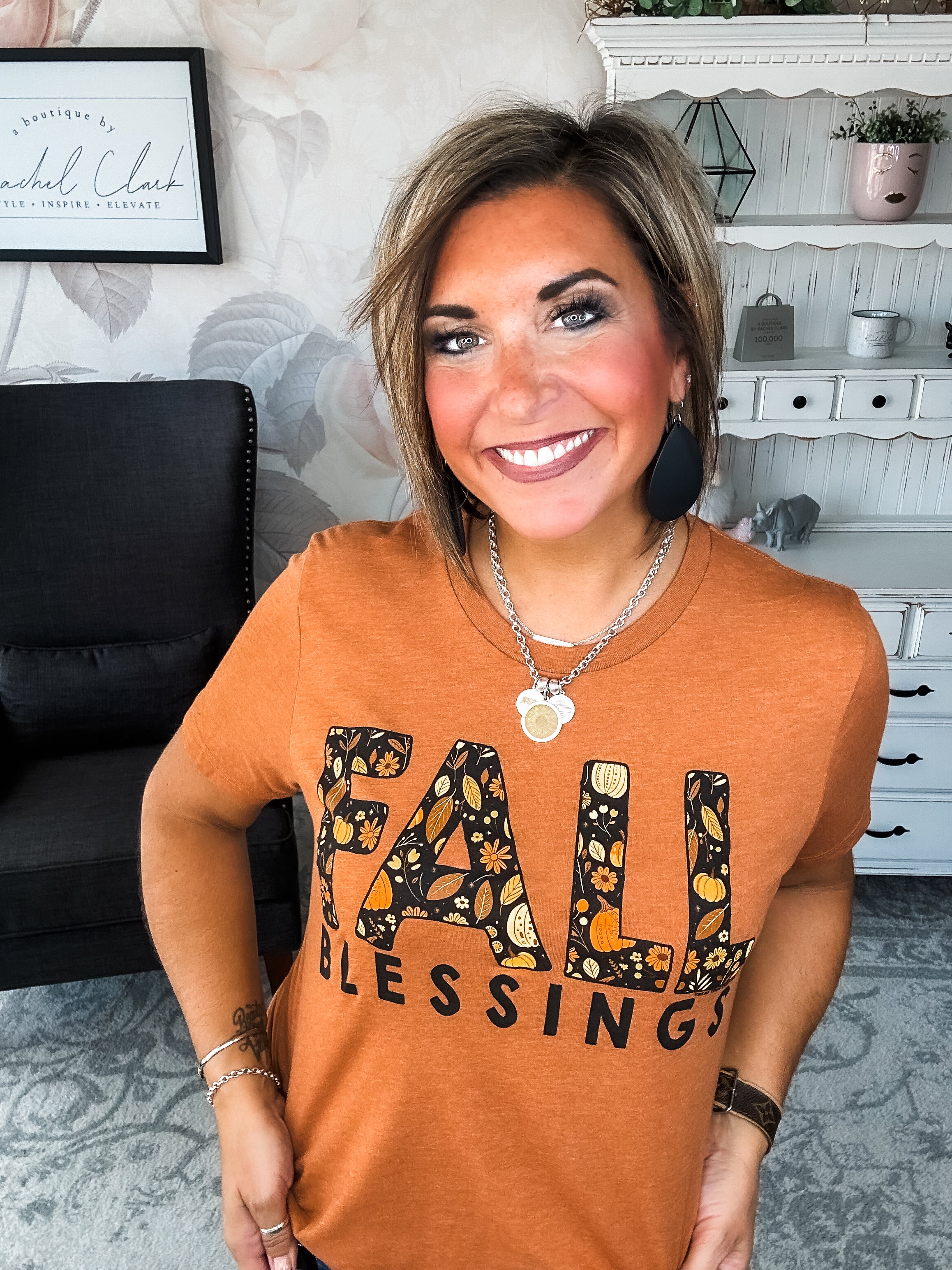 Woman wearing an orange t-shirt with 'Fall Blessings' with a leaf design.