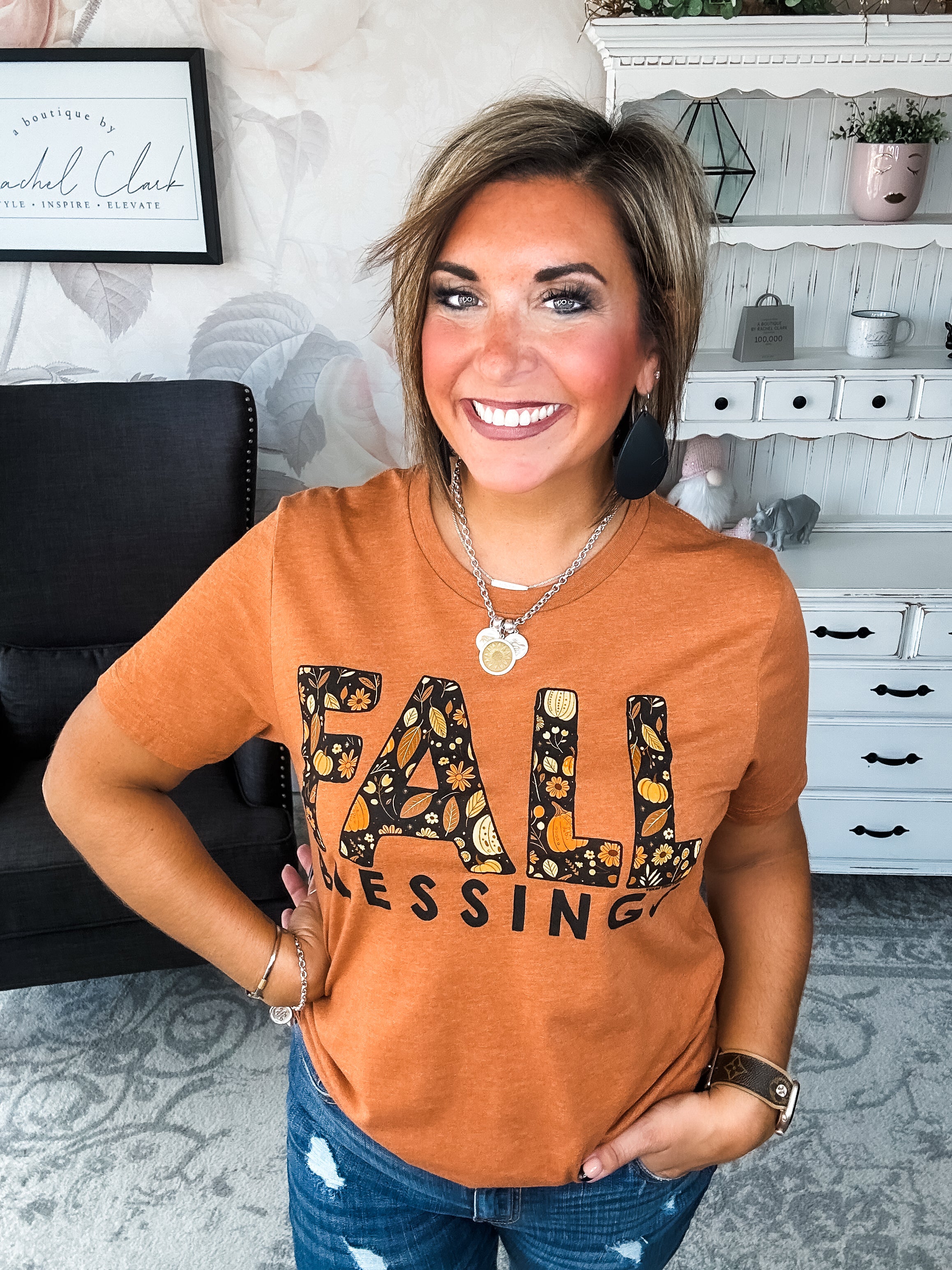 Woman wearing an orange t-shirt with 'Fall Blessings' with a leaf design.