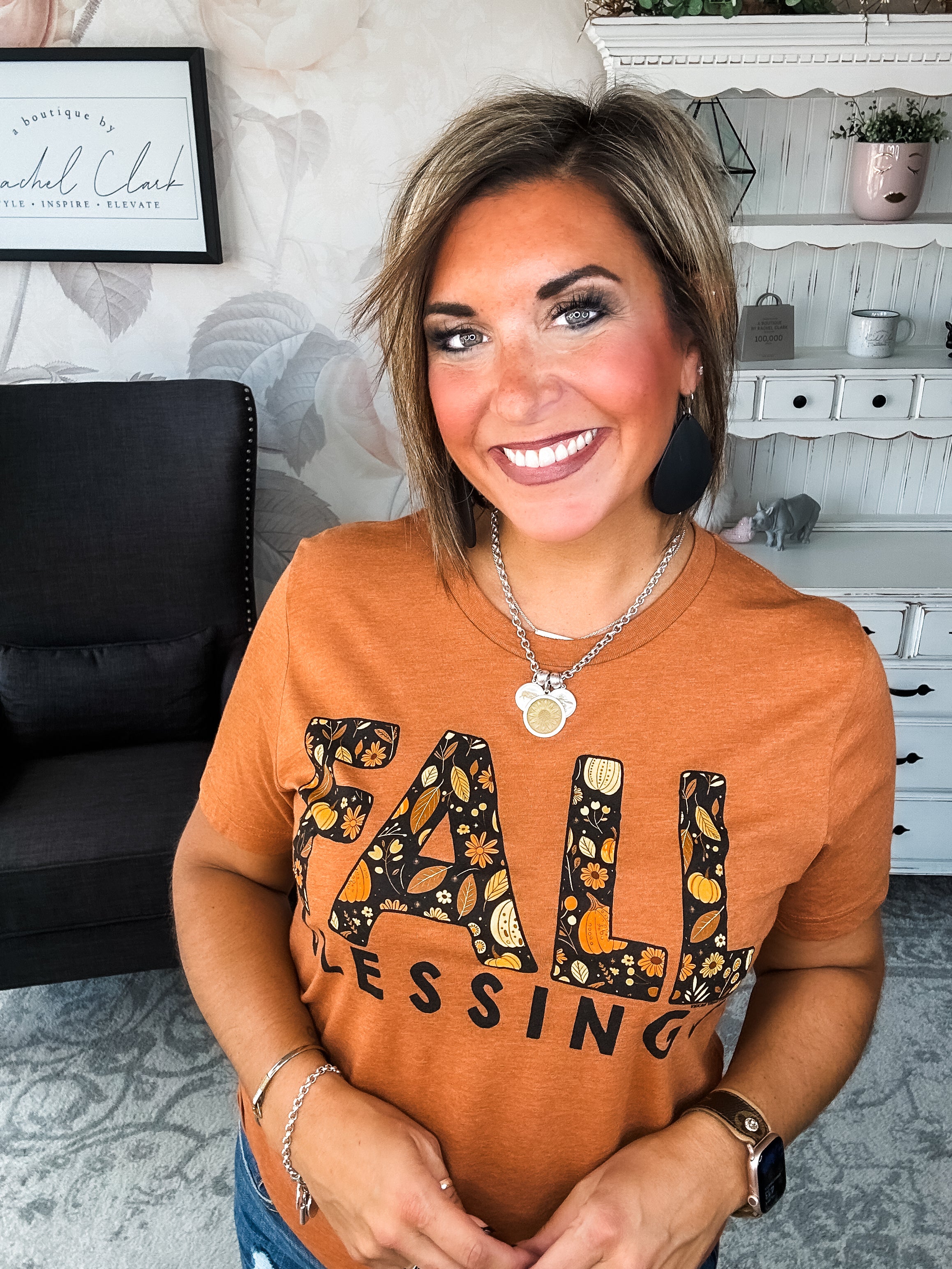 Woman wearing an orange t-shirt with 'Fall Blessings' with a leaf design.