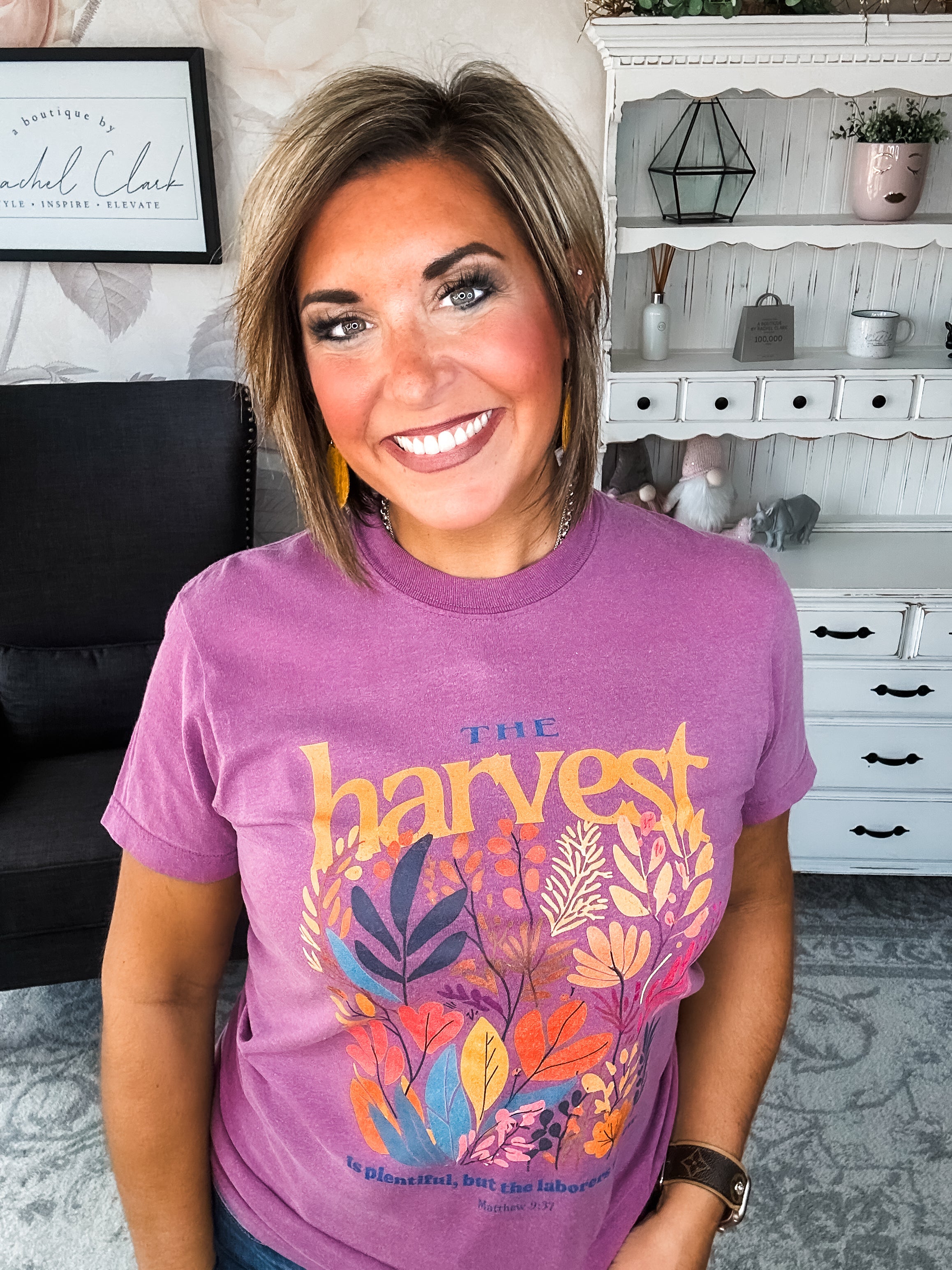 Woman wearing a purple t-shirt with floral designs that reads 'The Harvest is Plentiful, but the Laborers are Few, Matthew 9:37'