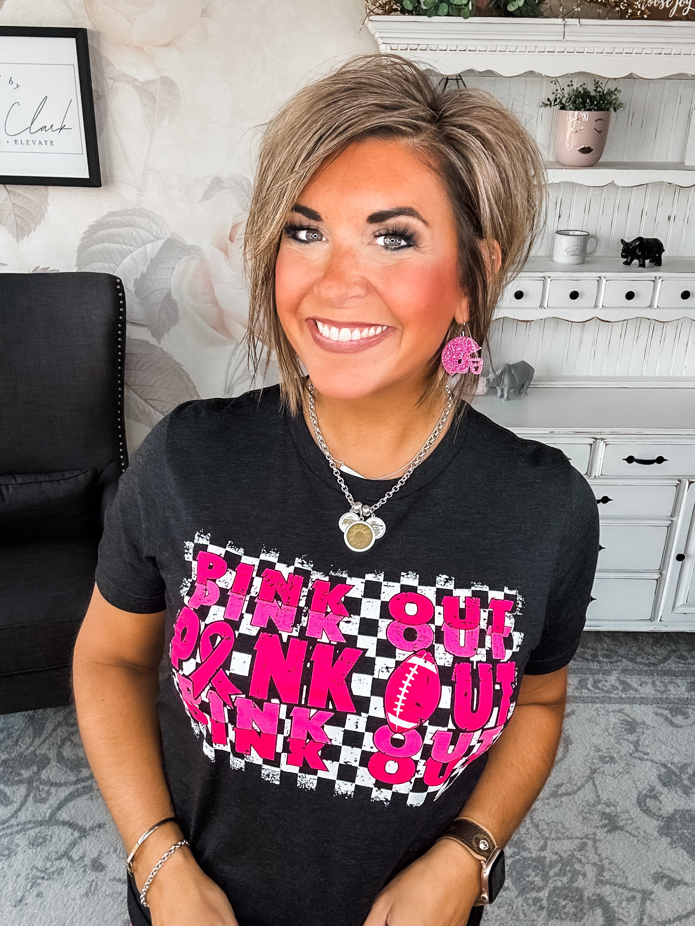 Woman wearing a black t-shirt with pink text that reads 'Pink Out' repeatedly with a football graphic.