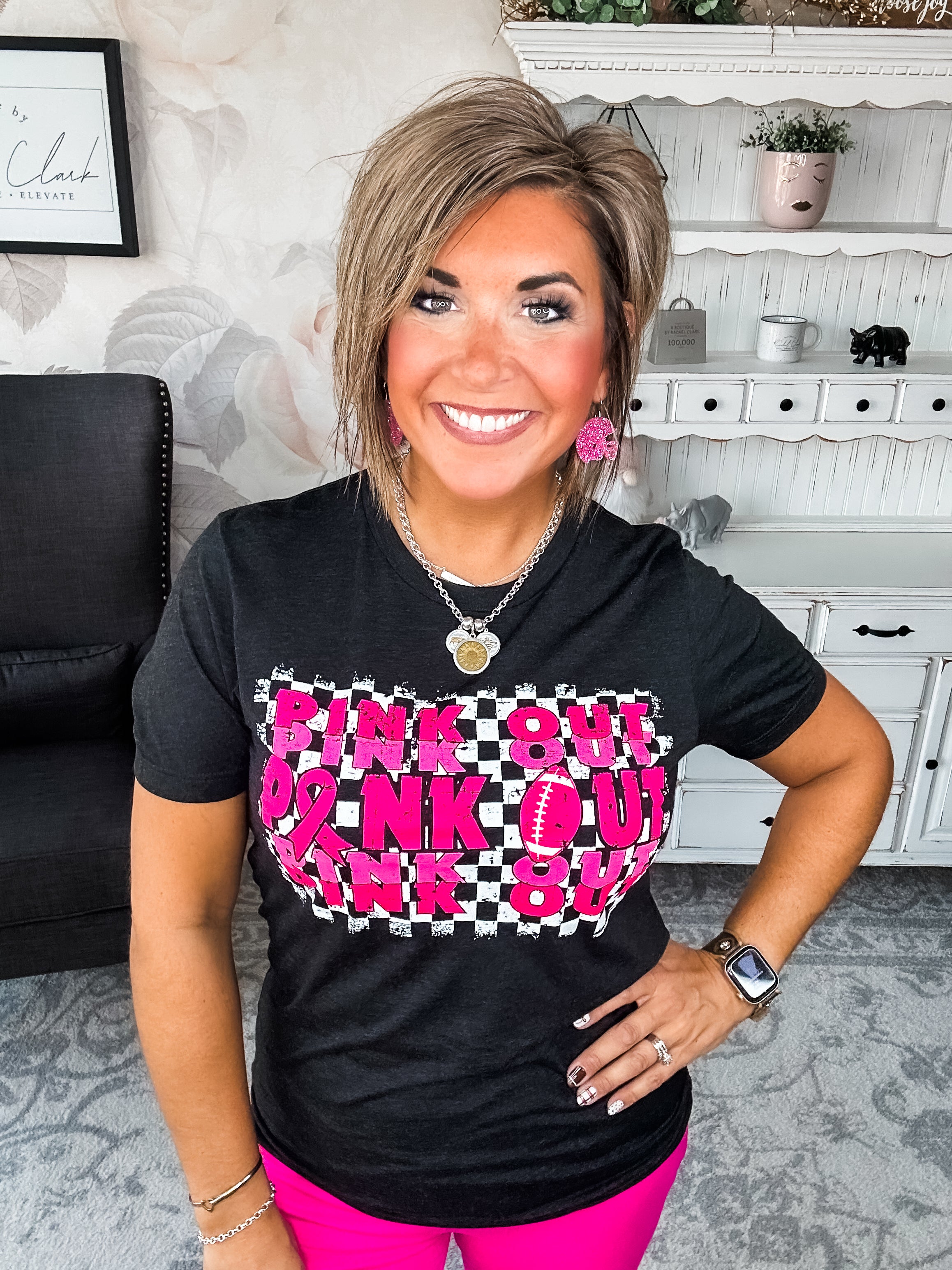 Woman wearing a black t-shirt with pink text that reads 'Pink Out' repeatedly with a football graphic.