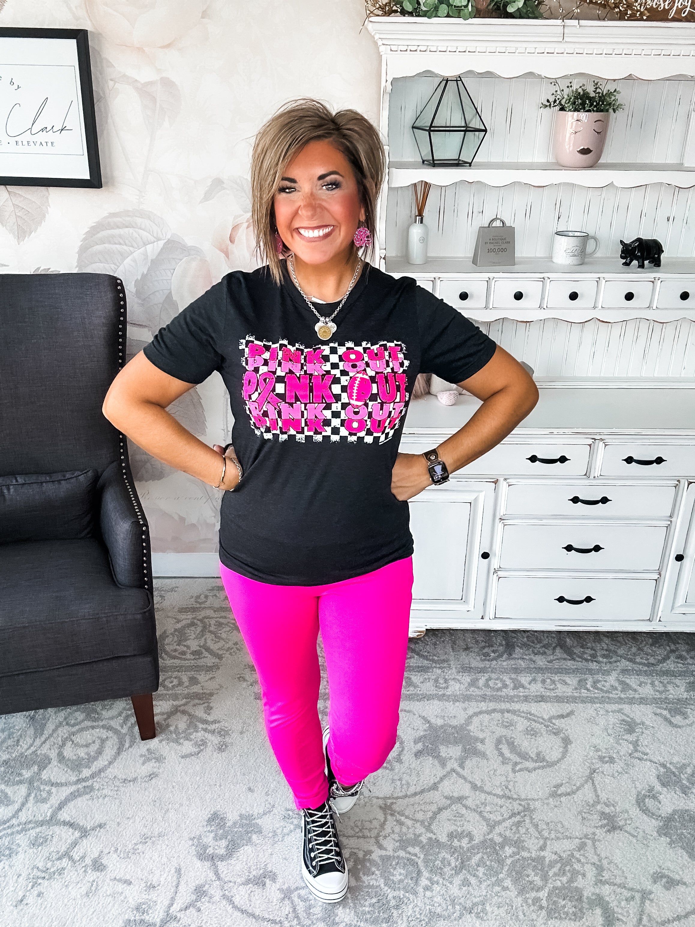 Woman wearing a black t-shirt with pink text that reads 'Pink Out' repeatedly with a football graphic.