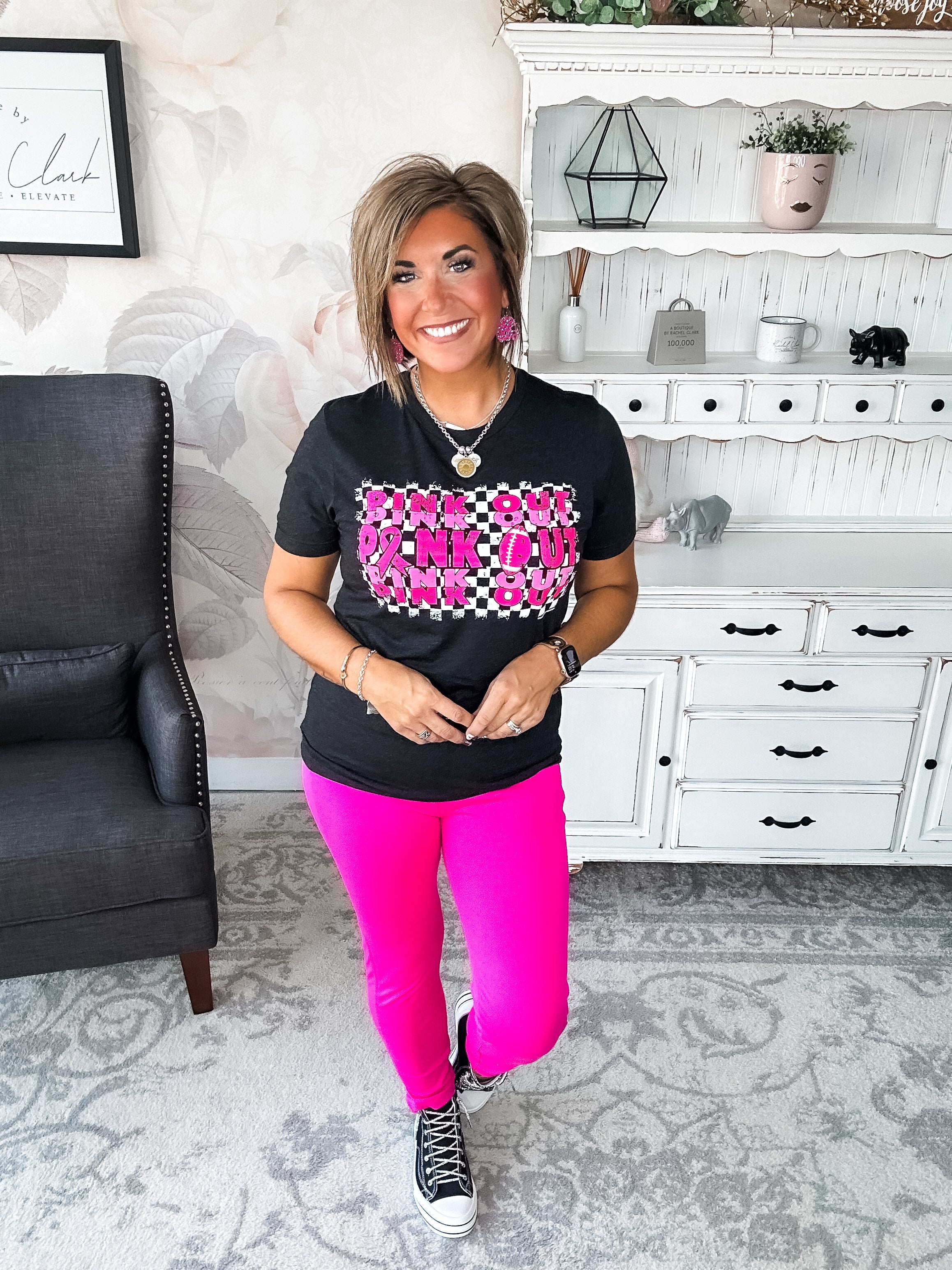 Woman wearing a black t-shirt with pink text that reads 'Pink Out' repeatedly with a football graphic.