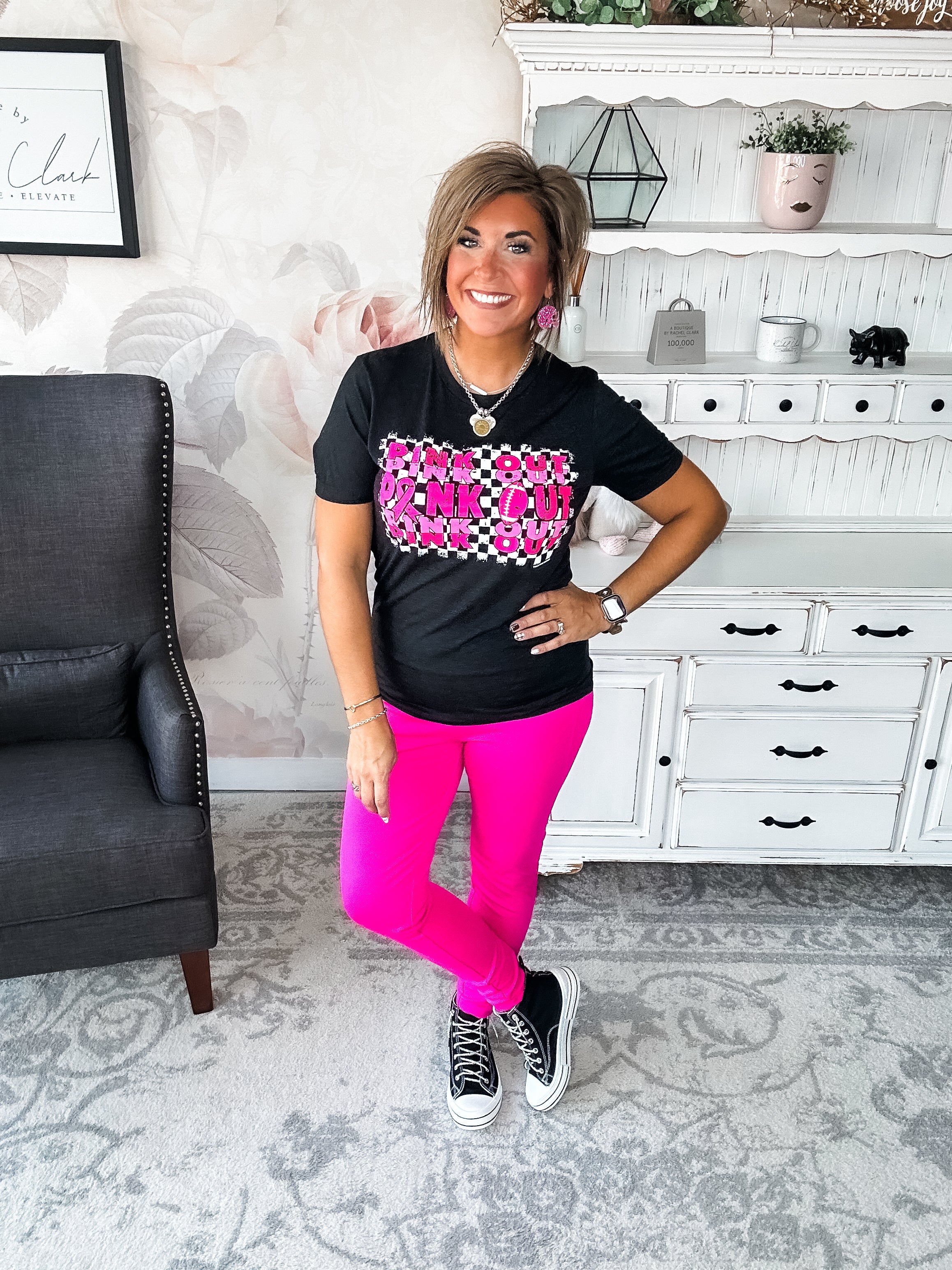 Woman wearing a black t-shirt with pink text that reads 'Pink Out' repeatedly with a football graphic.
