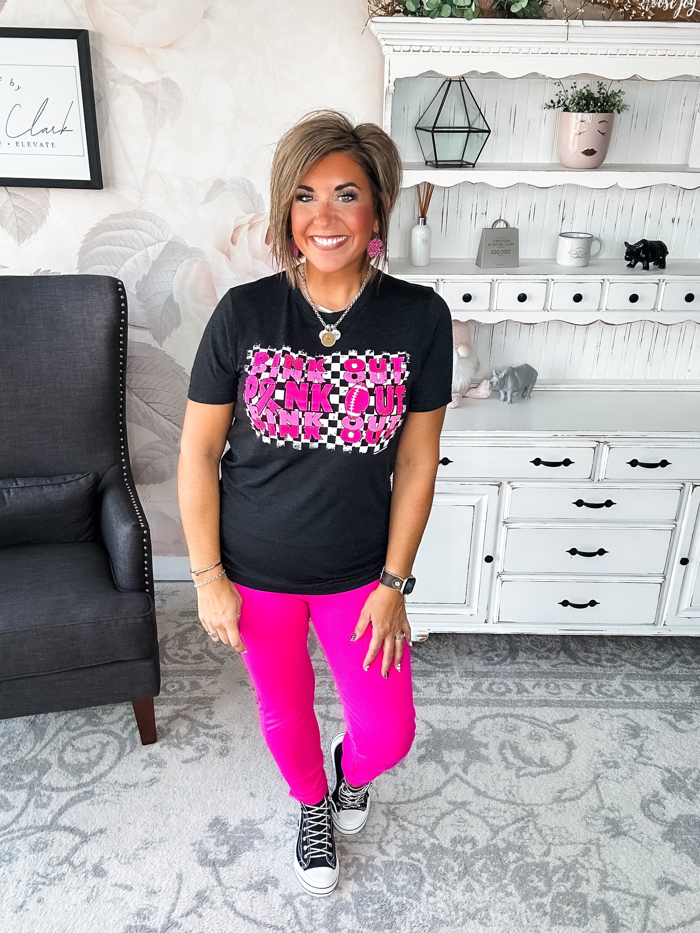 Woman wearing a black t-shirt with pink text that reads 'Pink Out' repeatedly with a football graphic.