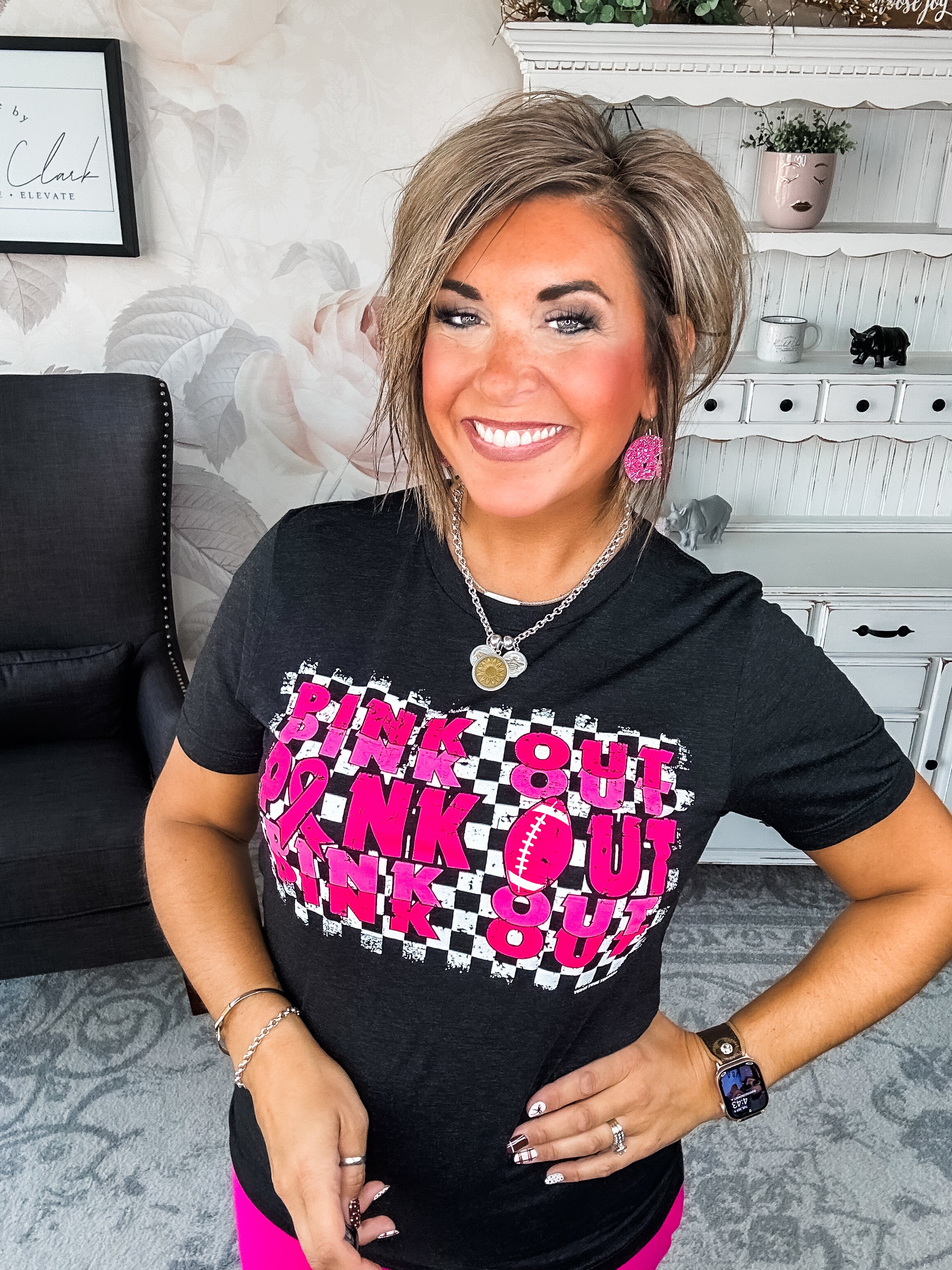 Woman wearing a black t-shirt with pink text that reads 'Pink Out' repeatedly with a football graphic.