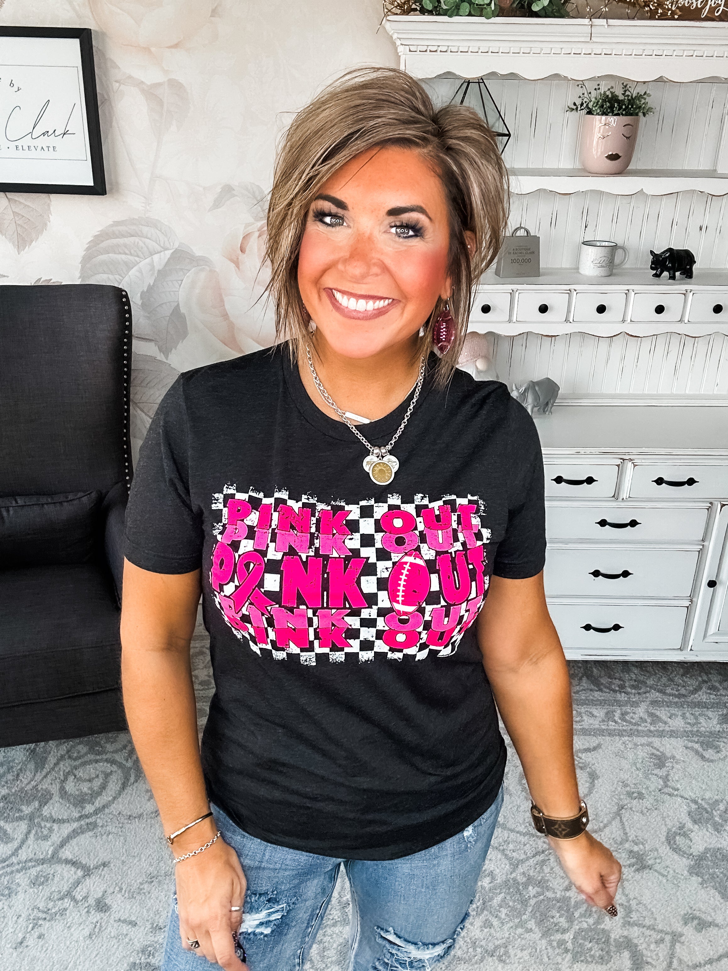 Woman wearing a black t-shirt with pink text that reads 'Pink Out' repeatedly with a football graphic.