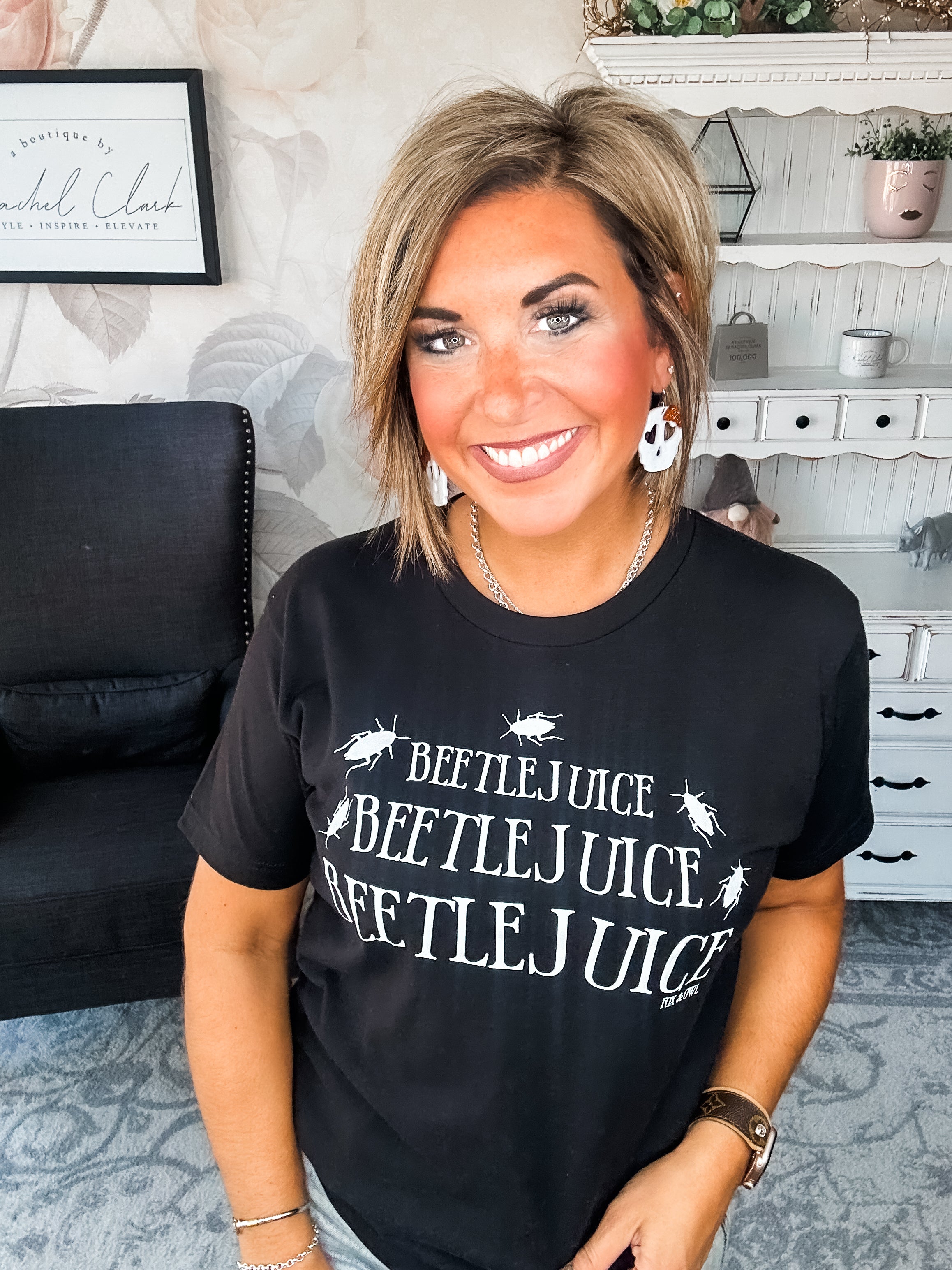 Woman wearing a black t-shirt that reads' Beetlejuice, Beetlejuice, Beetlejuice' with a beetle graphic design.