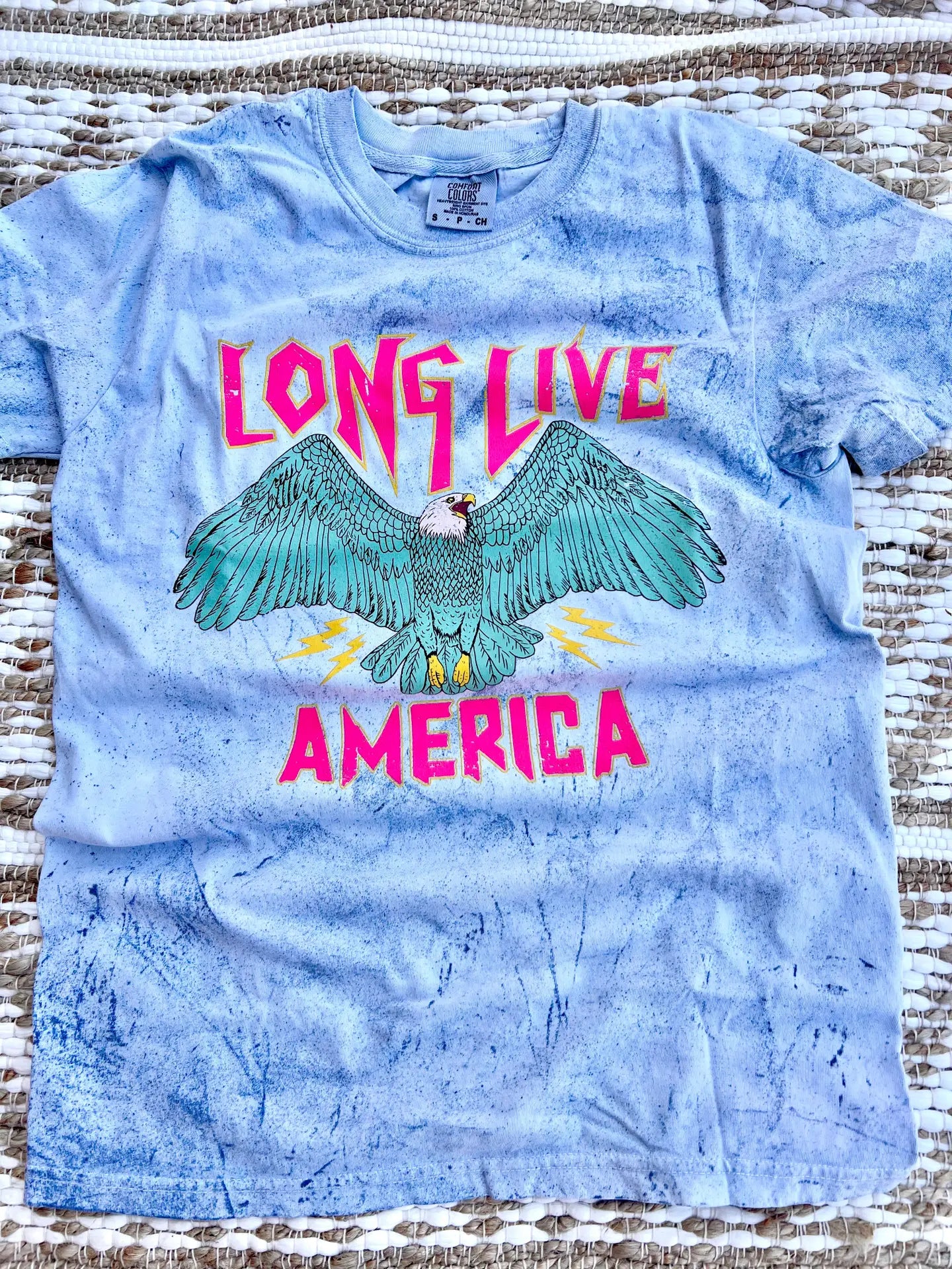 A crew-neck, short-sleeve graphic tee with the phrase 'LONG LIVE AMERICA' printed on it, in a bleached blue color.