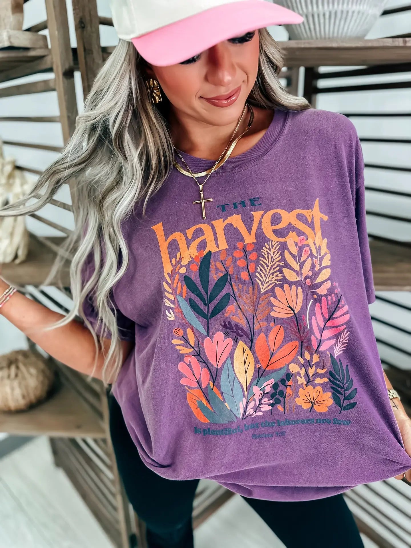 Woman wearing a purple t-shirt with floral designs that reads 'The Harvest is Plentiful, but the Laborers are Few, Matthew 9:37'