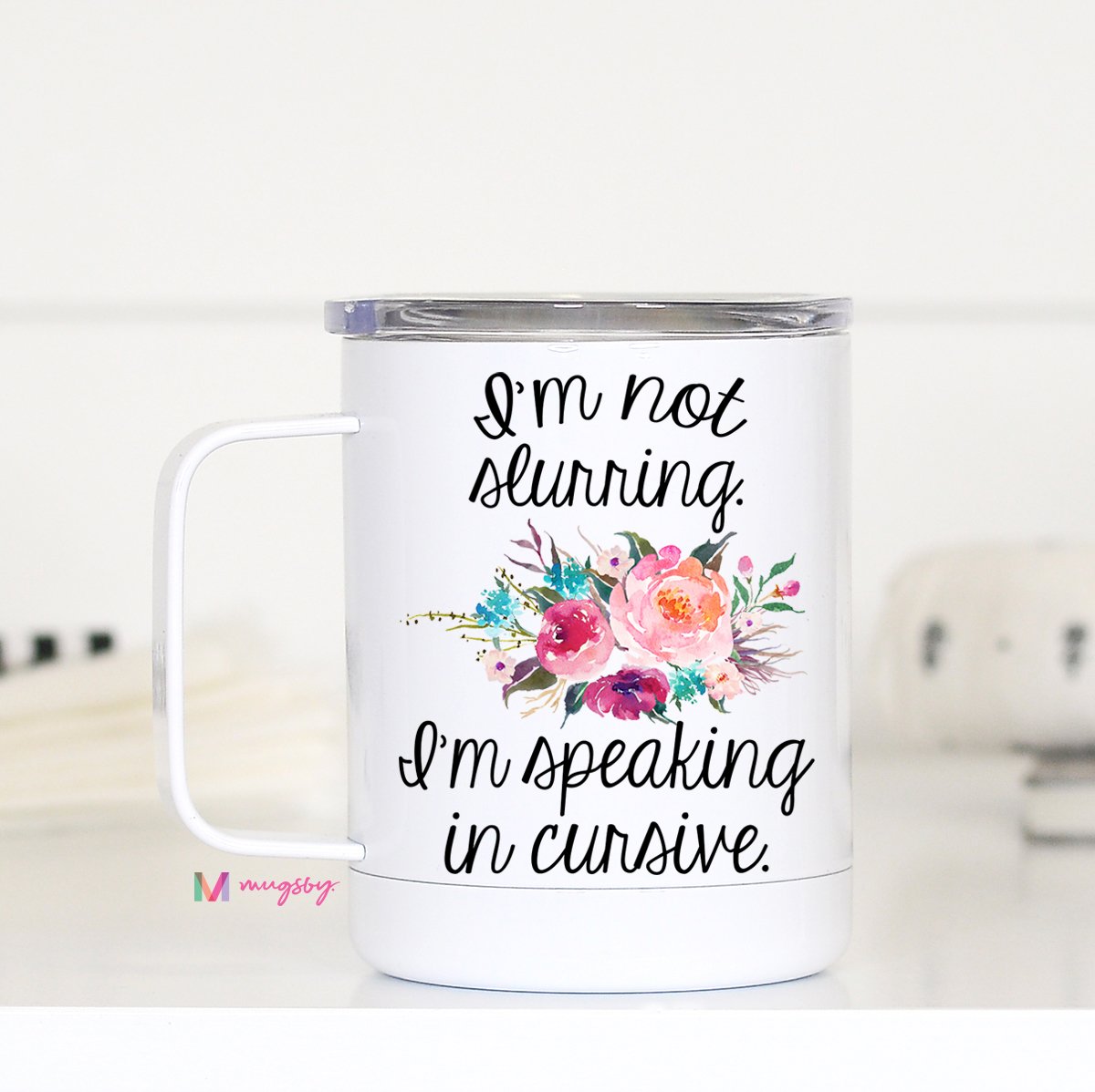 White stainless steel travel coffee mug with a floral graphic says 'I'm not slurring. I'm speaking in cursive.'