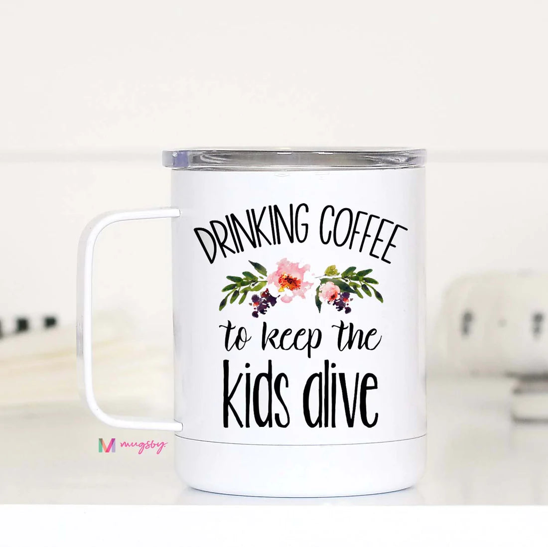 A white stainless steel travel mug with a text and floral design, featuring the phrase 'DRINKING COFFEE TO KEEP THE KIDS ALIVE'.