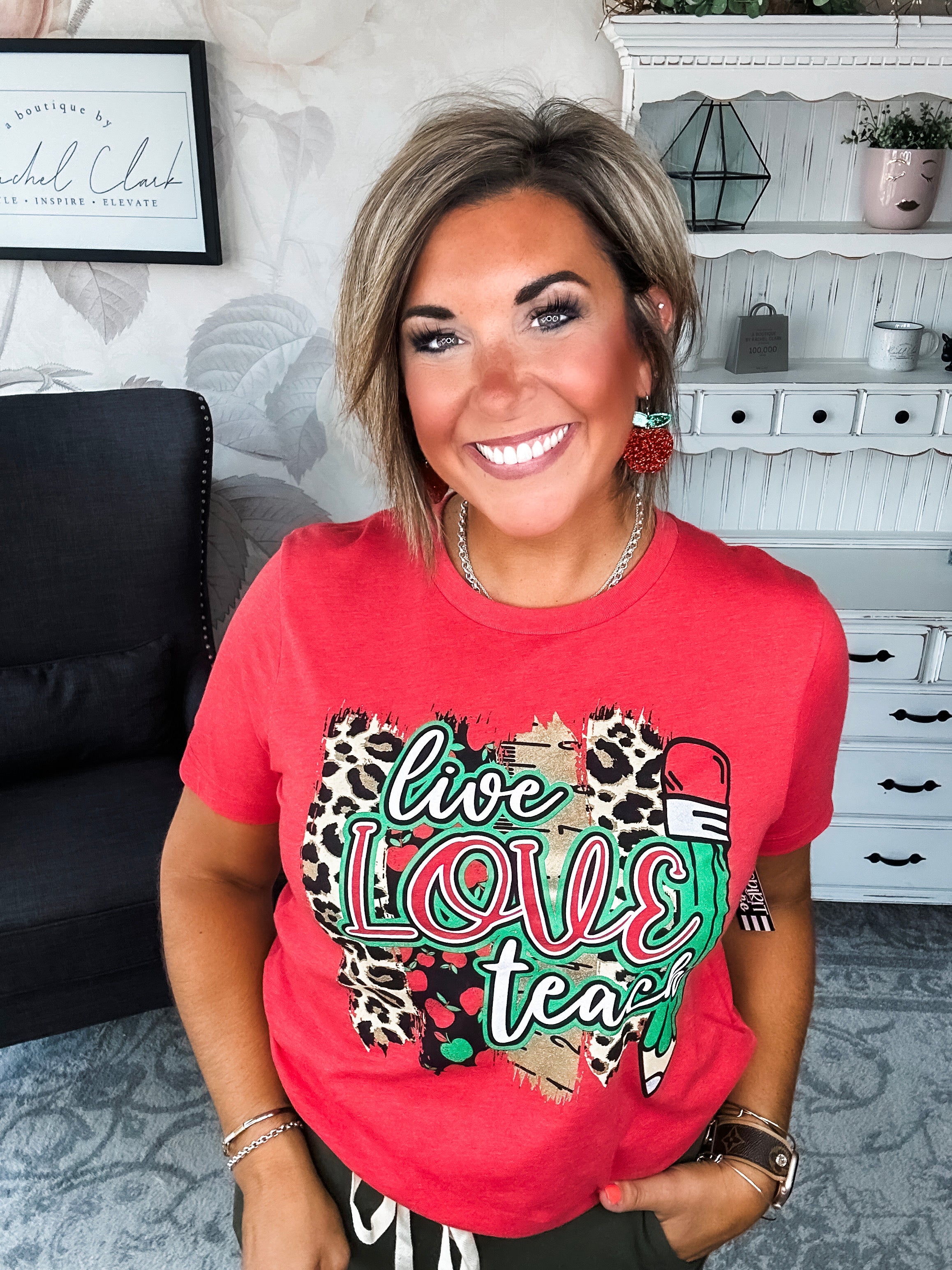 Woman wearing a red t-shirt with 'live love teach' design.
