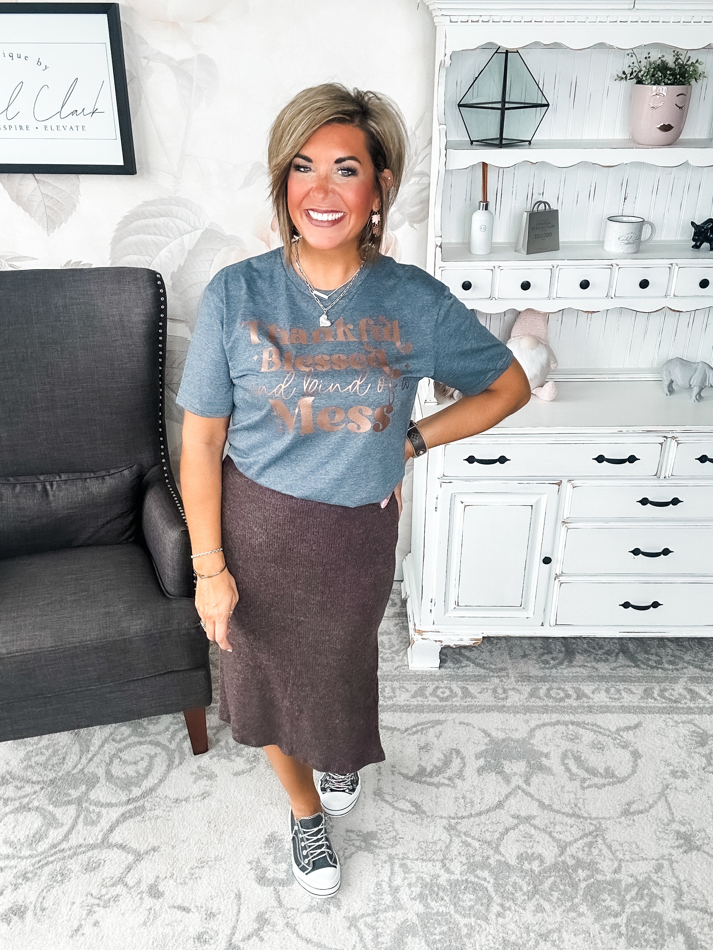 A woman wearing a grey t-shirt with the text 'Thankful Blessed and kind of a Mess' written in rose gold foil print.