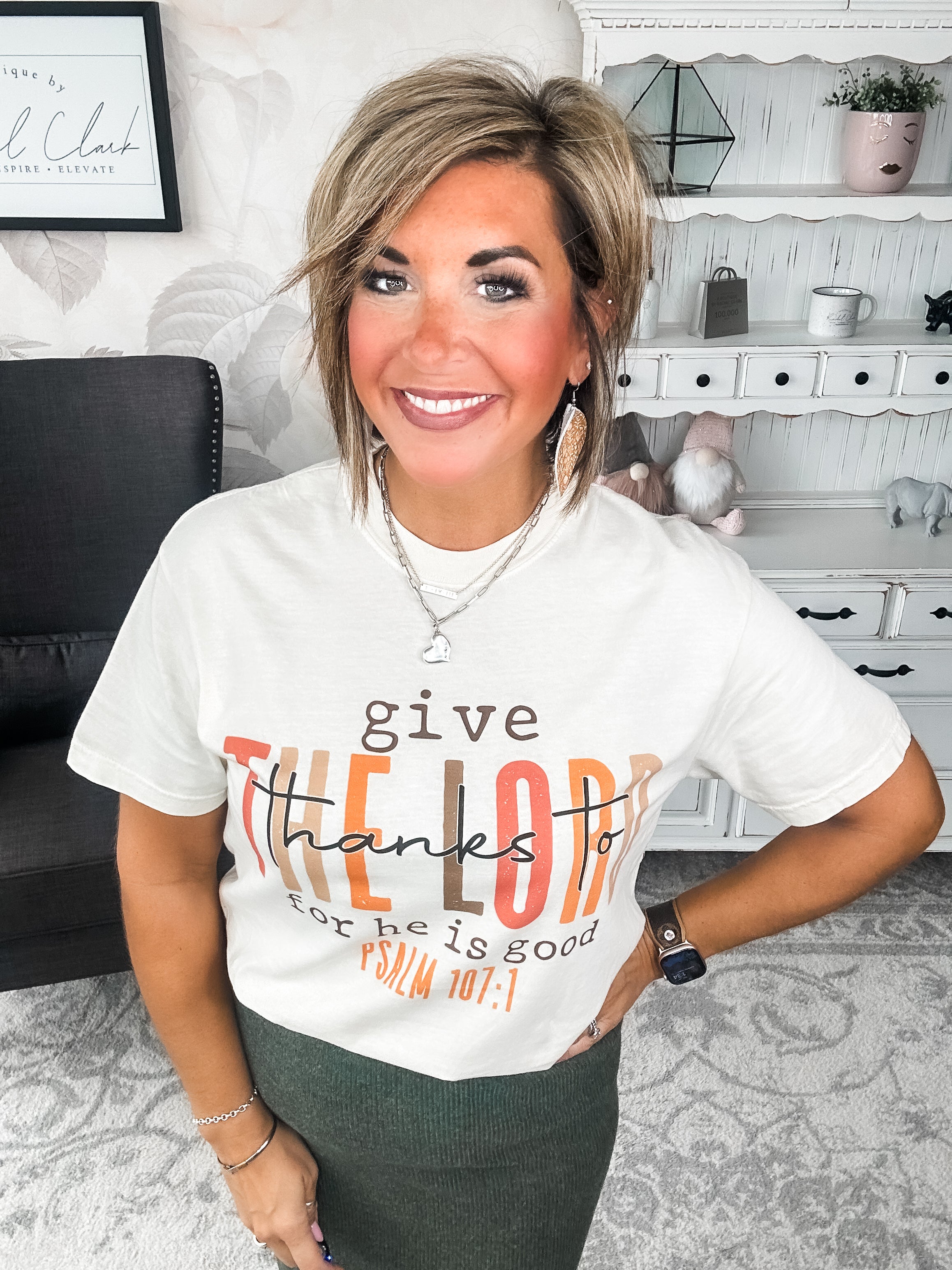 Woman wearing a cream t-shirt that reads 'give thanks to the Lord for he is good. Psalm 107:1'