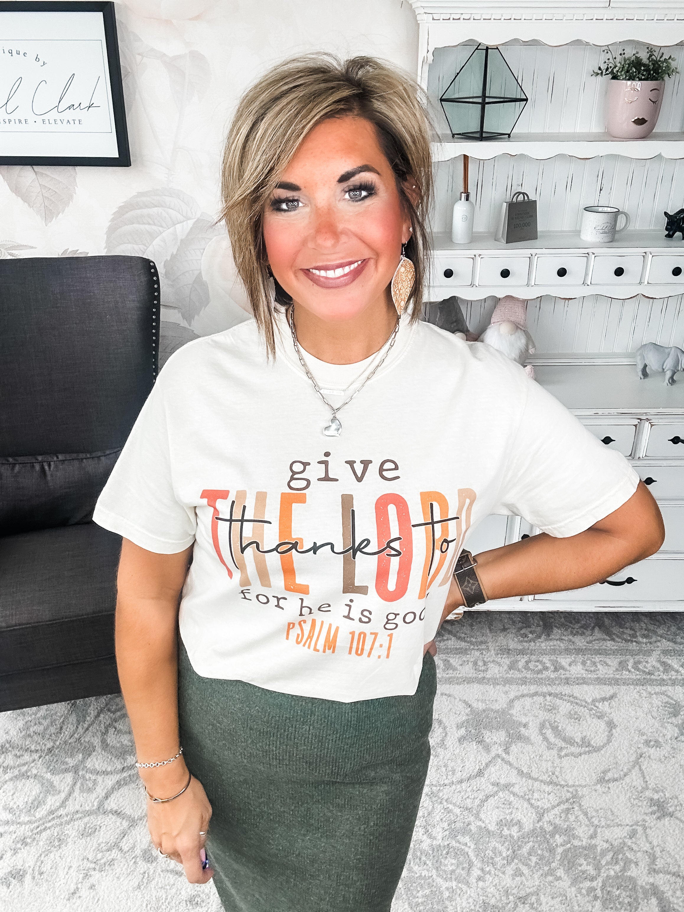 Woman wearing a cream t-shirt that reads 'give thanks to the Lord for he is good. Psalm 107:1'