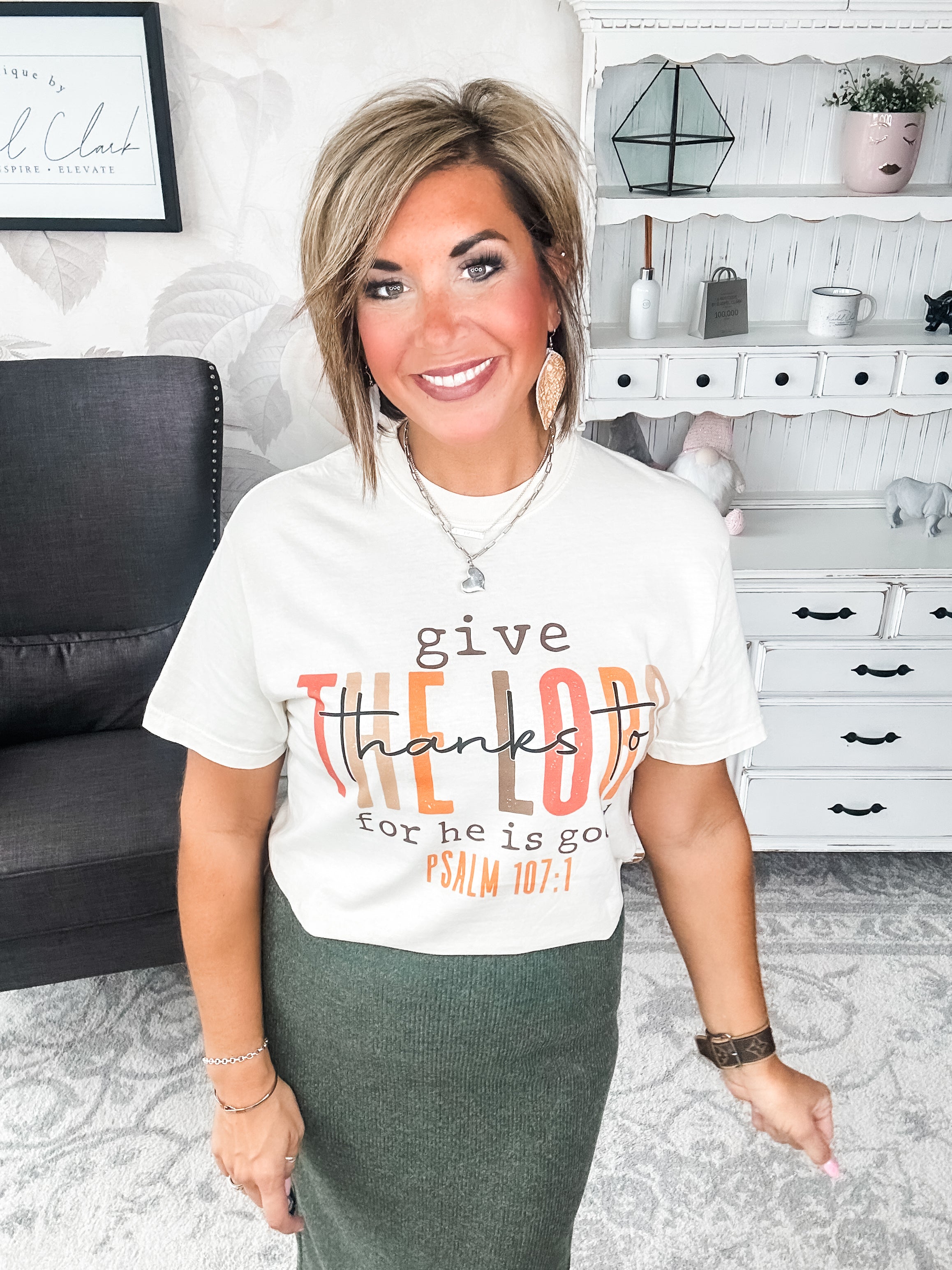 Woman wearing a cream t-shirt that reads 'give thanks to the Lord for he is good. Psalm 107:1'