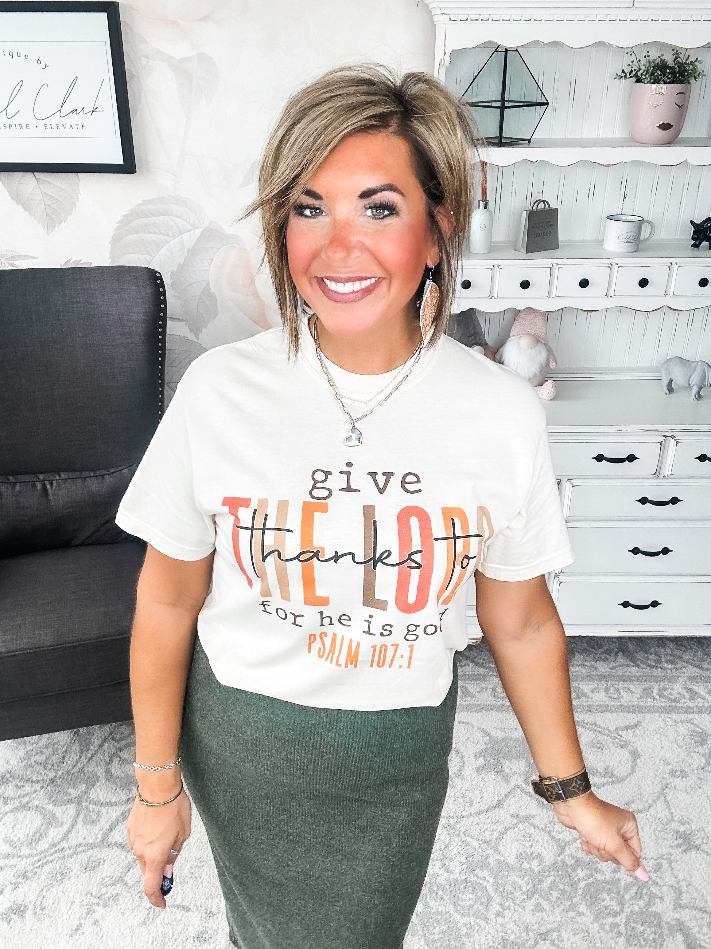 Woman wearing a cream t-shirt that reads 'give thanks to the Lord for he is good. Psalm 107:1'
