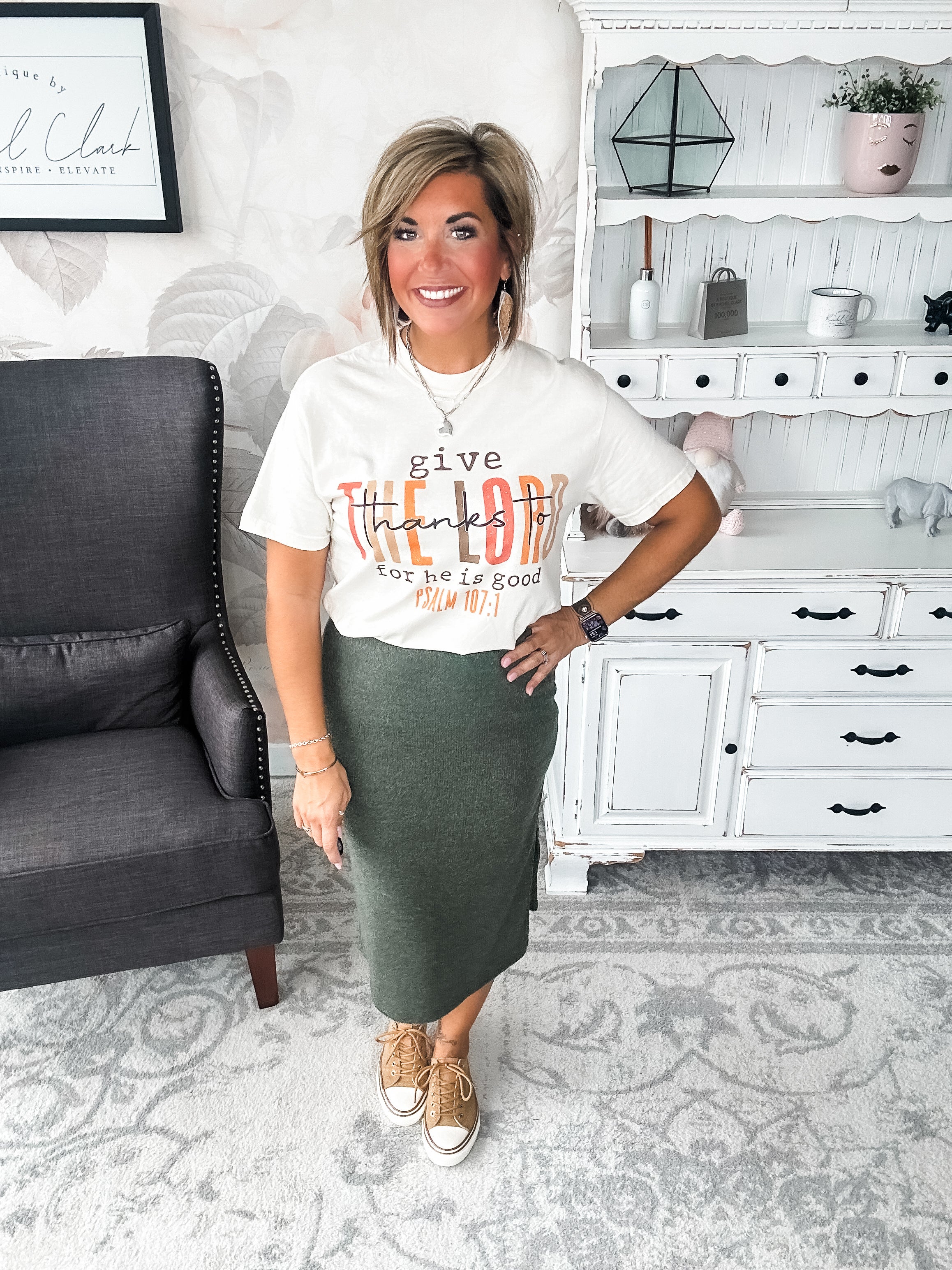 Woman wearing a cream t-shirt that reads 'give thanks to the Lord for he is good. Psalm 107:1'