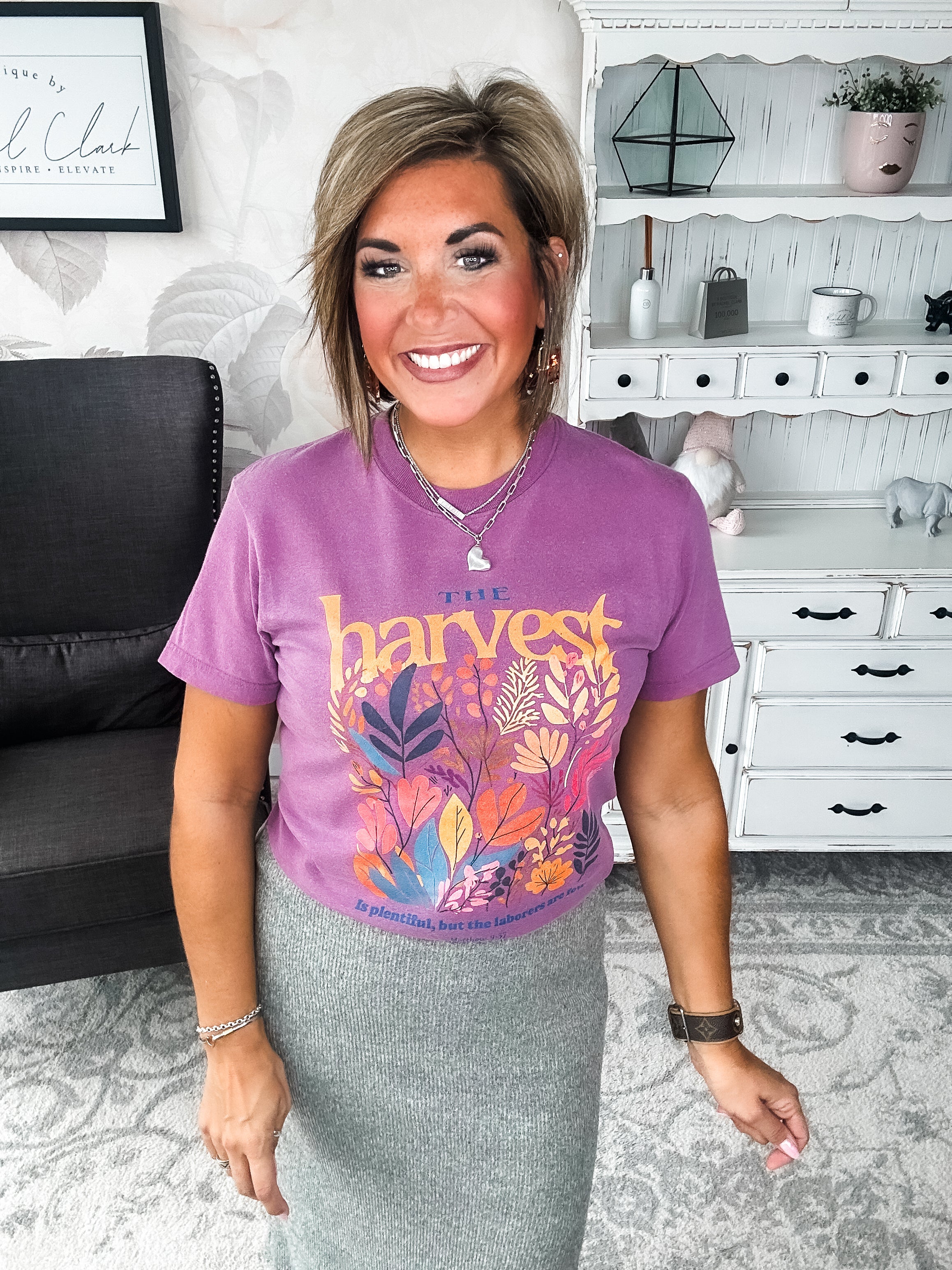 Woman wearing a purple t-shirt with floral designs that reads 'The Harvest is Plentiful, but the Laborers are Few, Matthew 9:37'