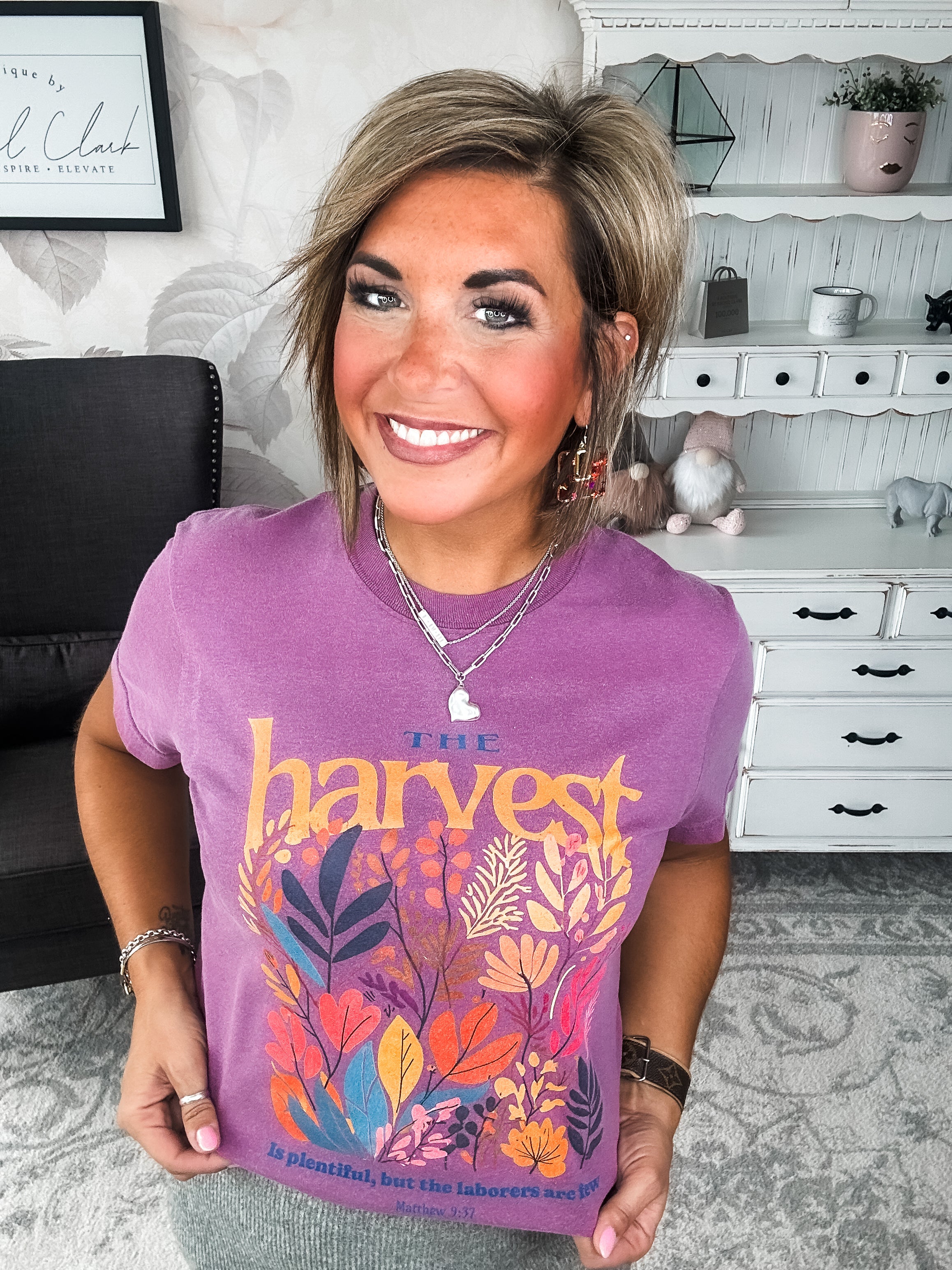 Woman wearing a purple t-shirt with floral designs that reads 'The Harvest is Plentiful, but the Laborers are Few, Matthew 9:37'