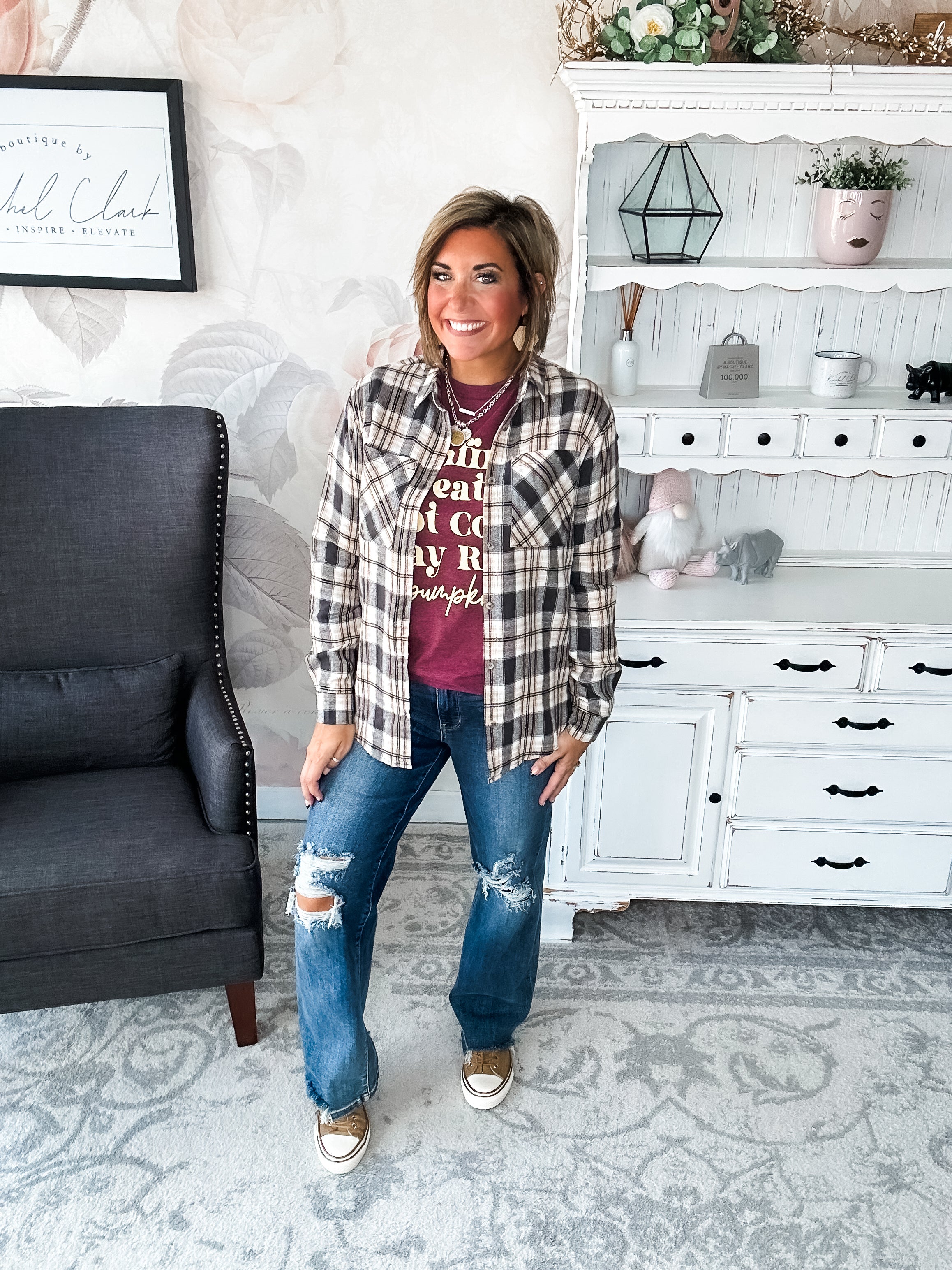 Woman wearing a maroon t-shirt that reads,  'Bonfires, Sweaters, Hot cocoa, Hay Rides and Pumpkins.' written in a cream text. 