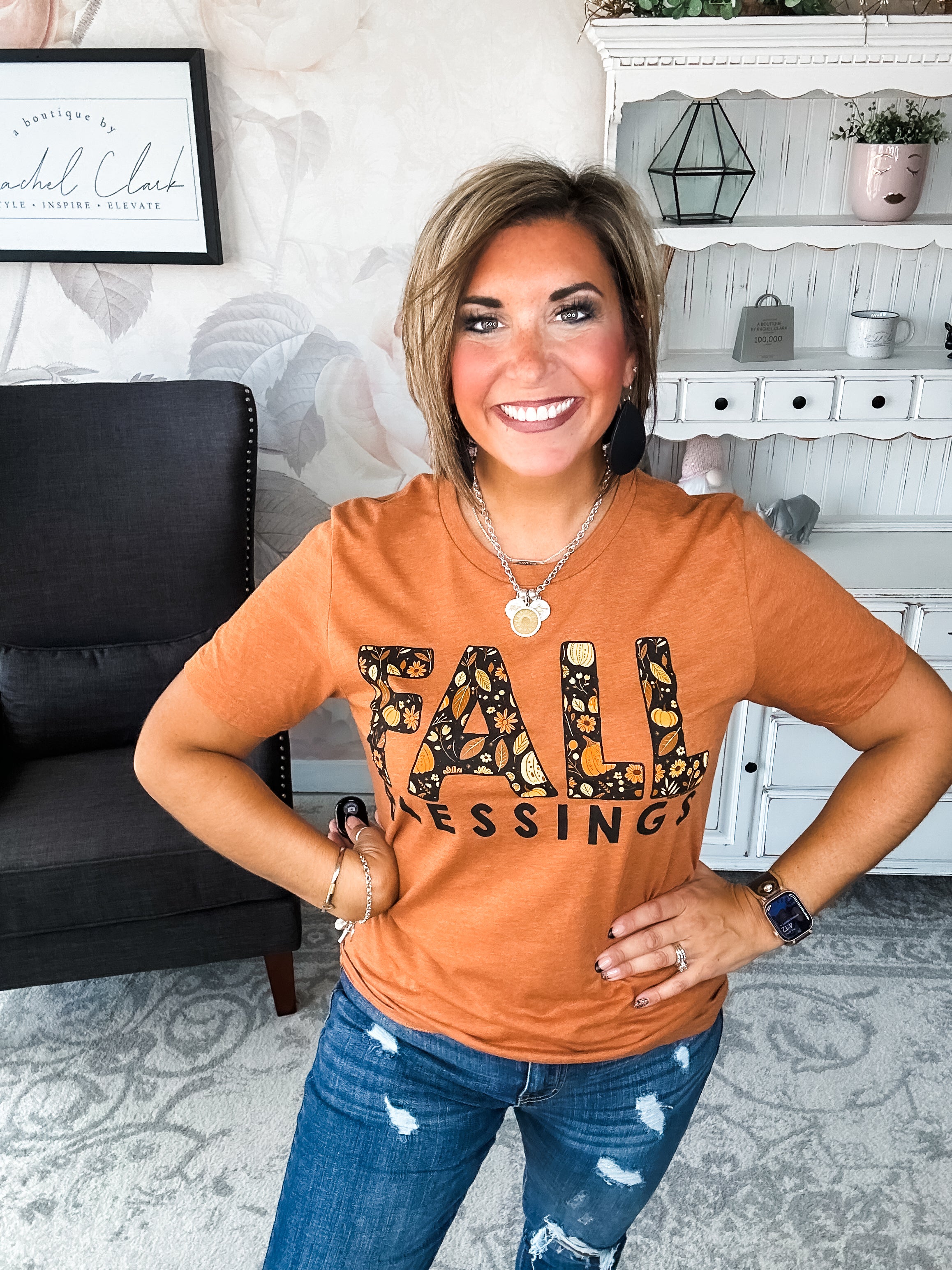Woman wearing an orange t-shirt with 'Fall Blessings' with a leaf design.