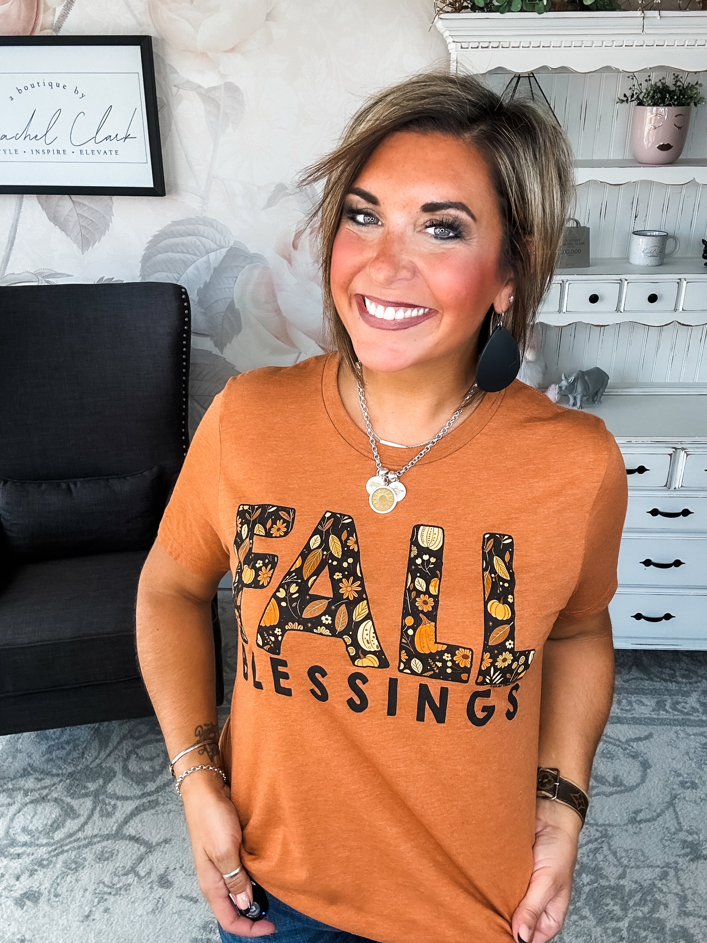 Woman wearing an orange t-shirt with 'Fall Blessings' with a leaf design.