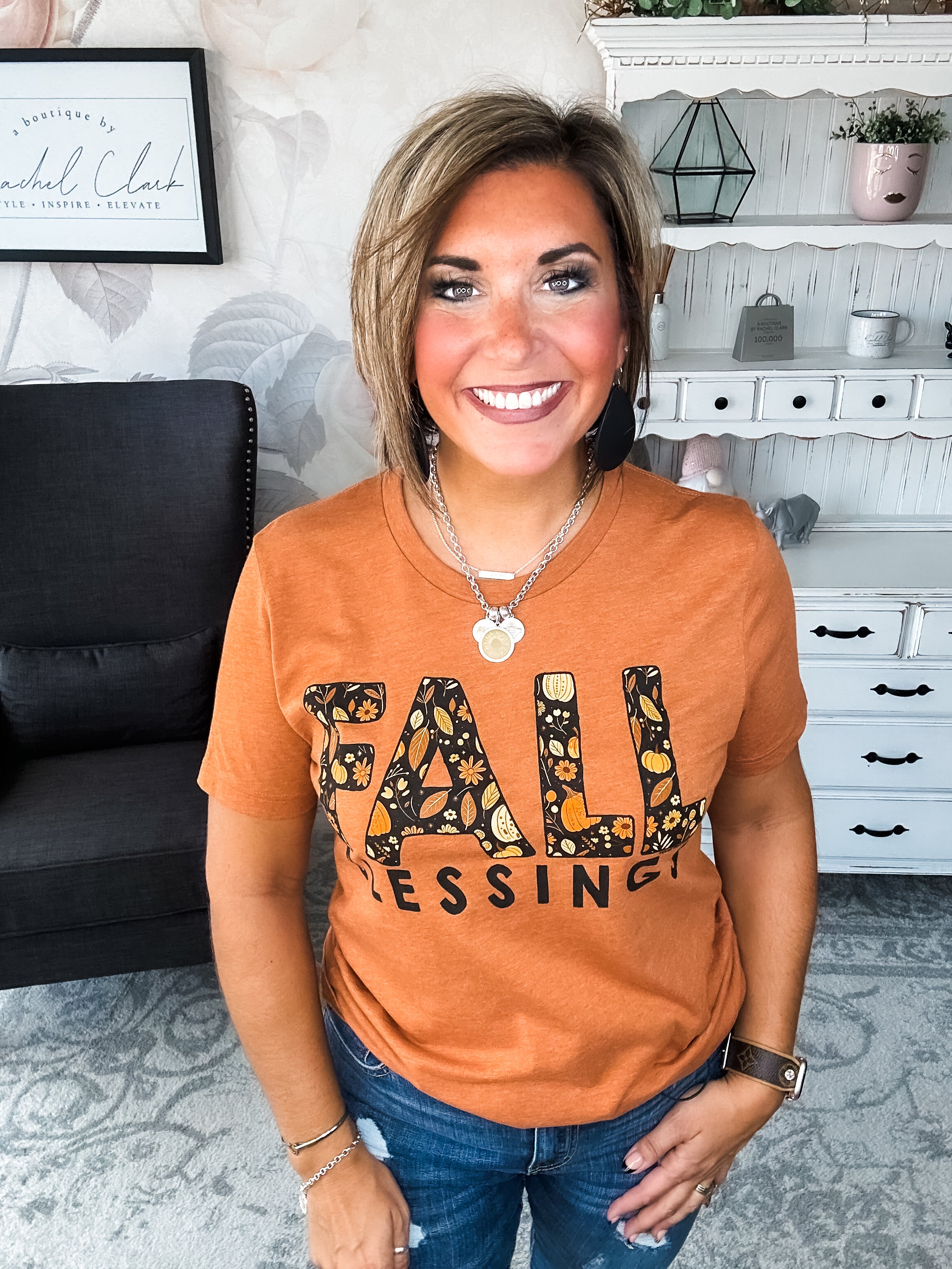 Woman wearing an orange t-shirt with 'Fall Blessings' with a leaf design.