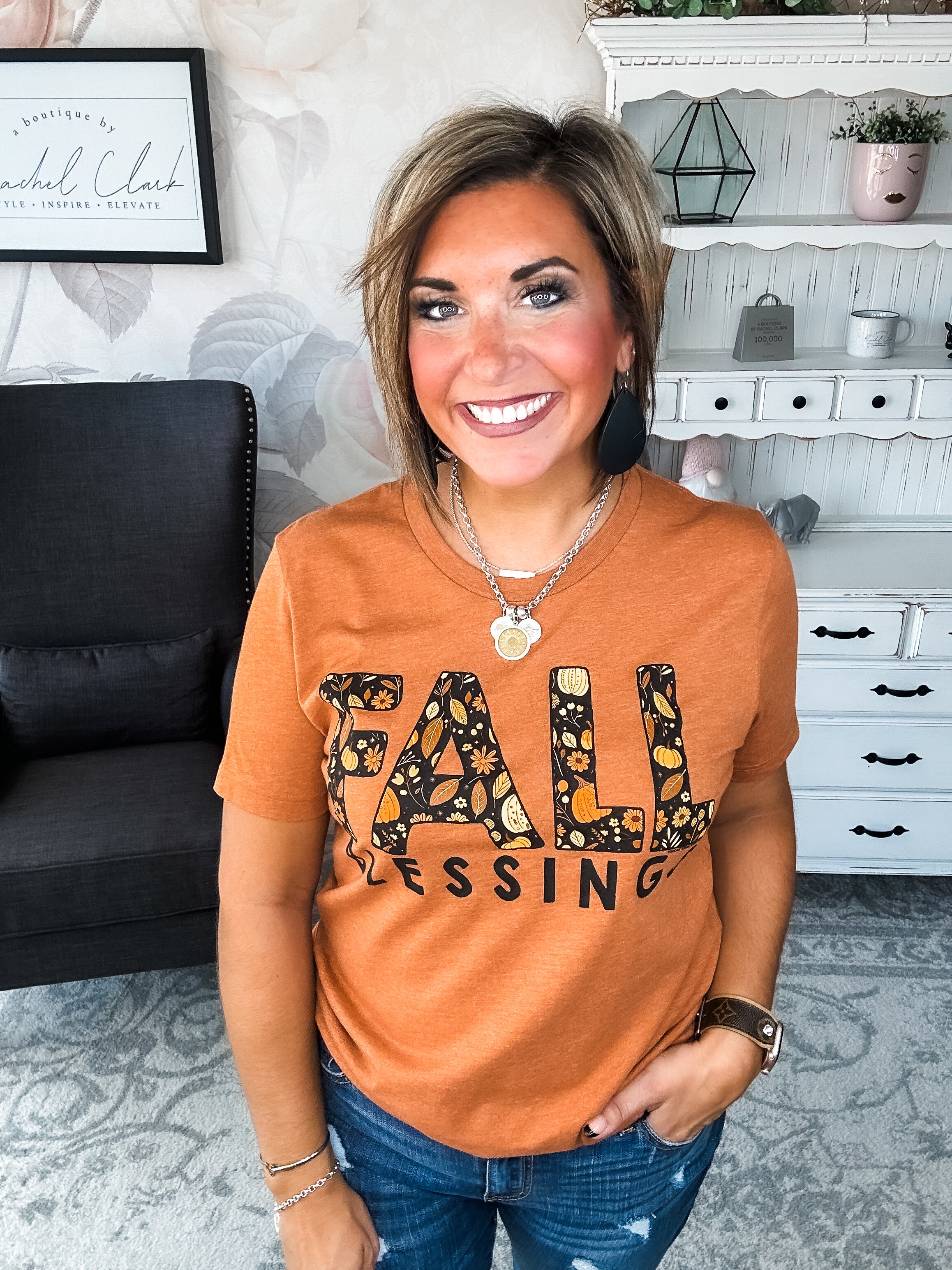 Woman wearing an orange t-shirt with 'Fall Blessings' with a leaf design.