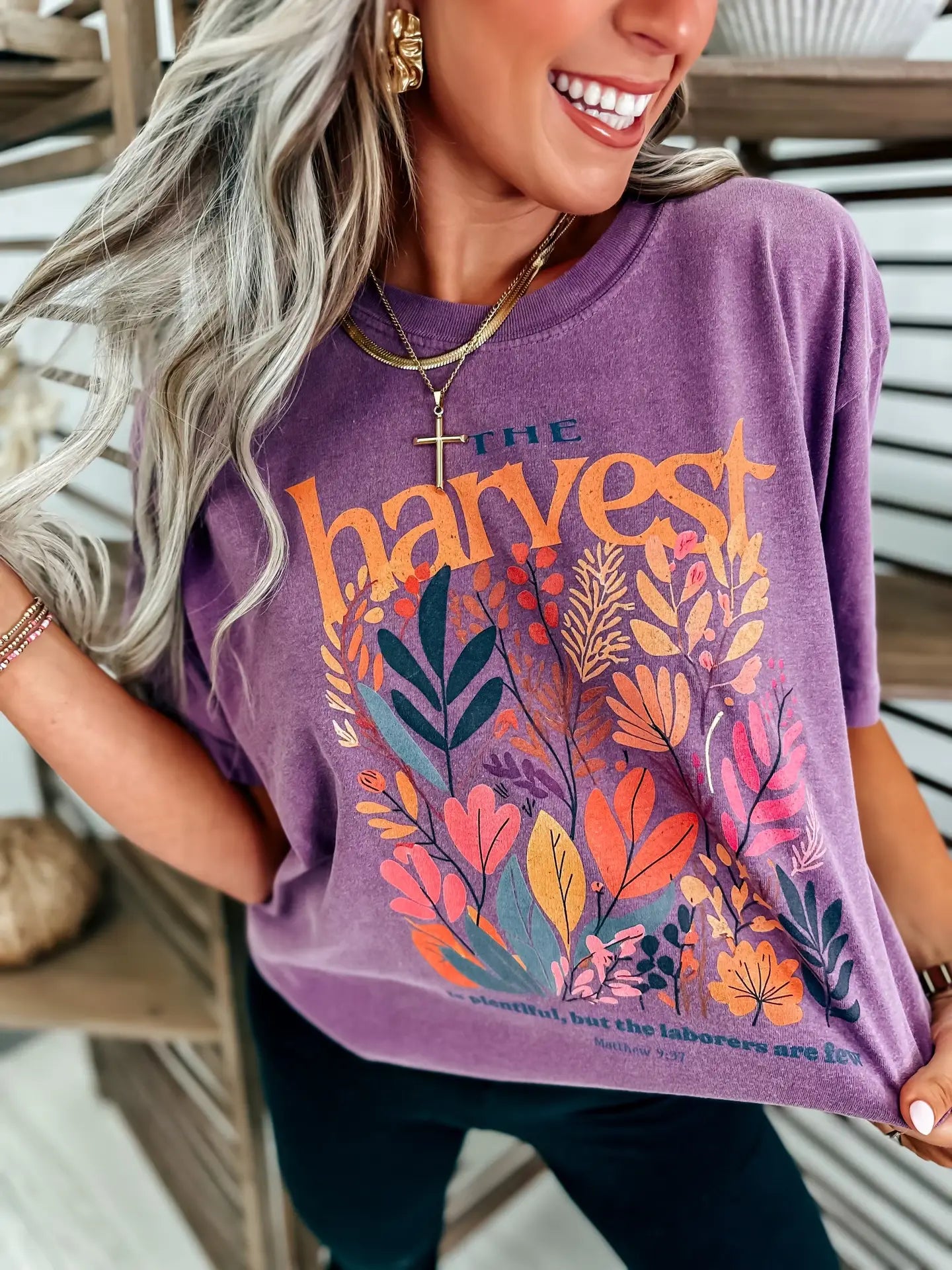 Woman wearing a purple t-shirt with floral designs that reads 'The Harvest is Plentiful, but the Laborers are Few, Matthew 9:37'